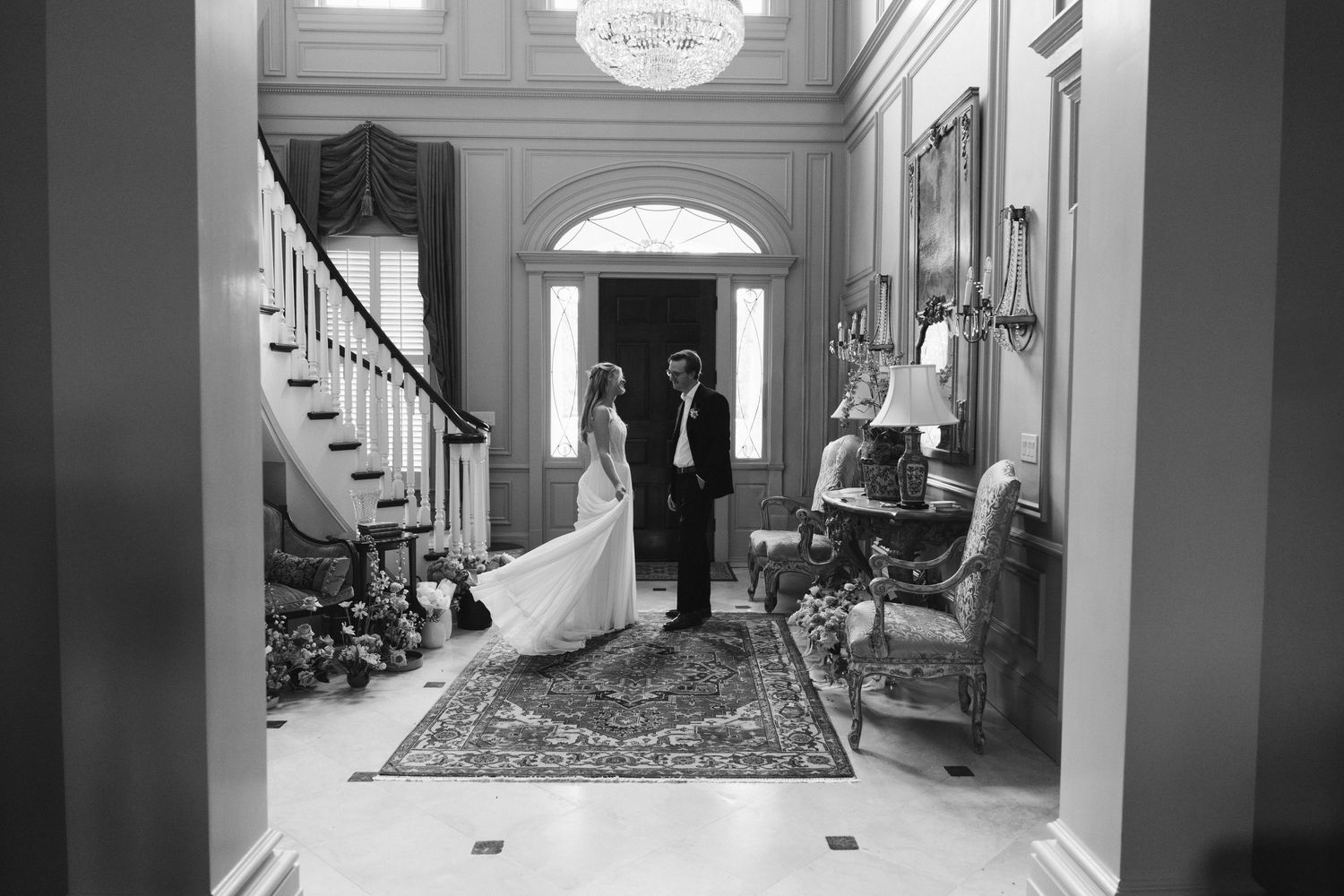 Black and white photo of bride and groom sharing first look in grand estate foyer.
