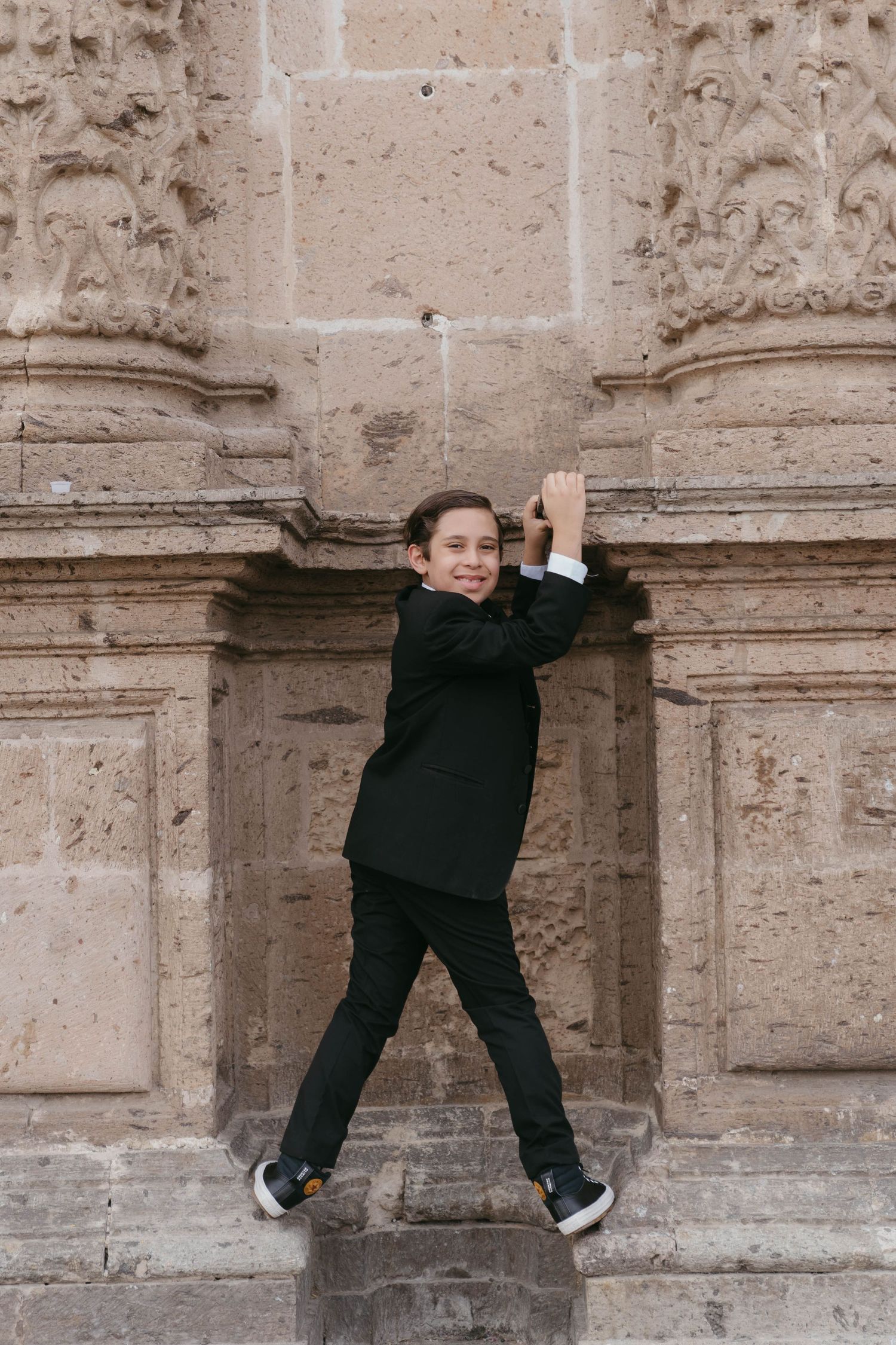 Playful pose against a textured stone wall of historic architecture.
