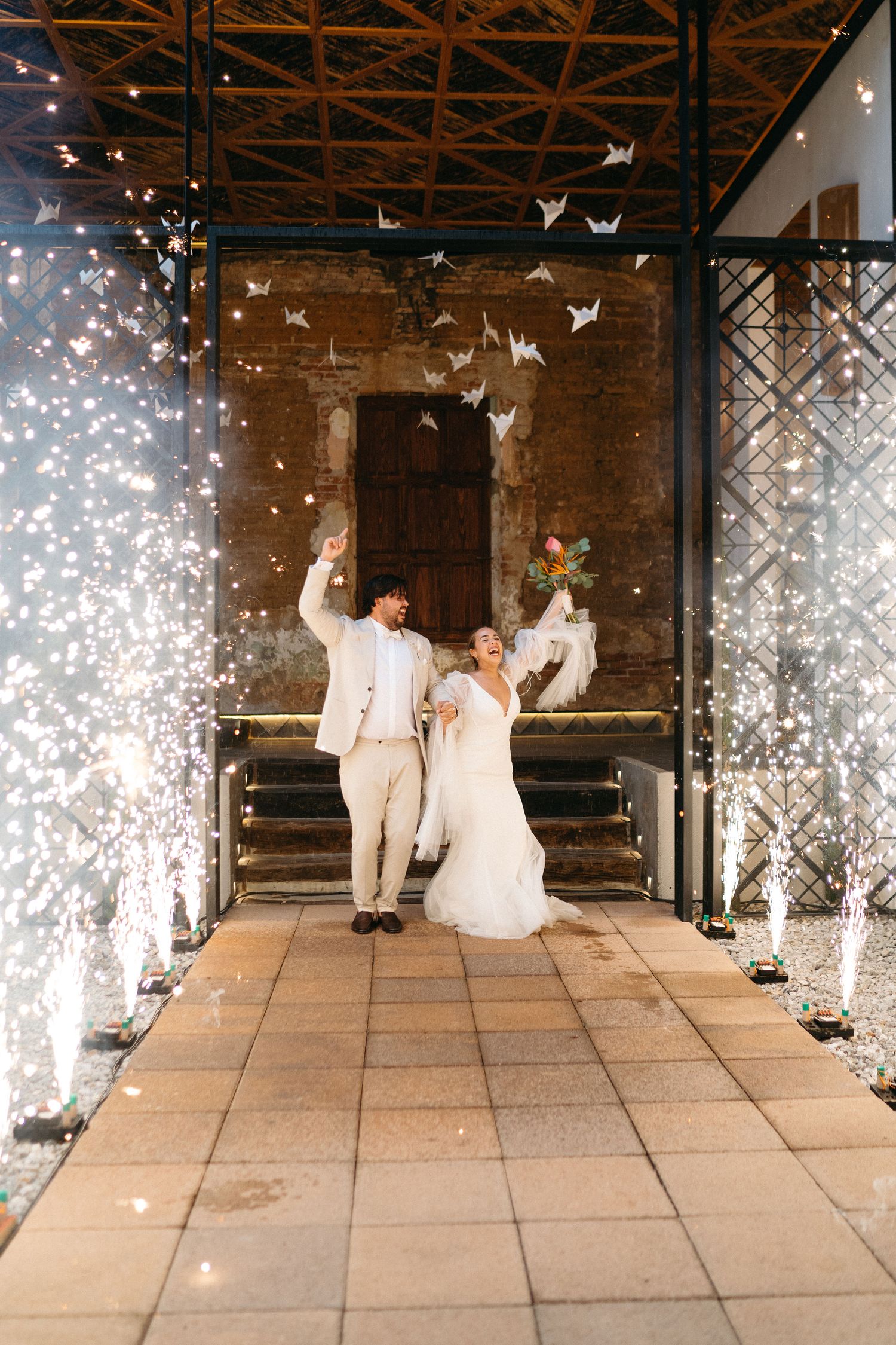 Wedding couple sits on stage with sparkler effects creating magical atmosphere.