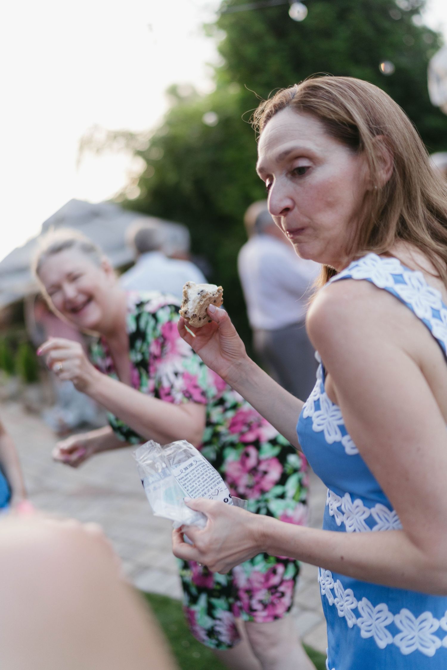 Wedding guests in floral dresses enjoying outdoor celebration activities.