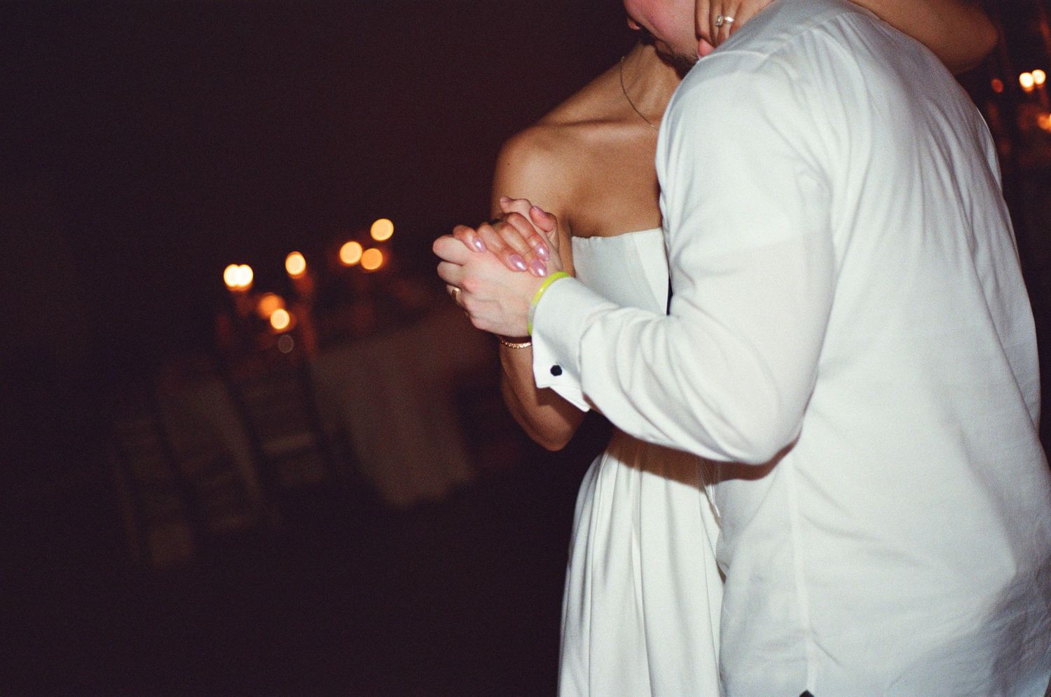 Wedding couples dance in intimate moments during a darkly lit reception.