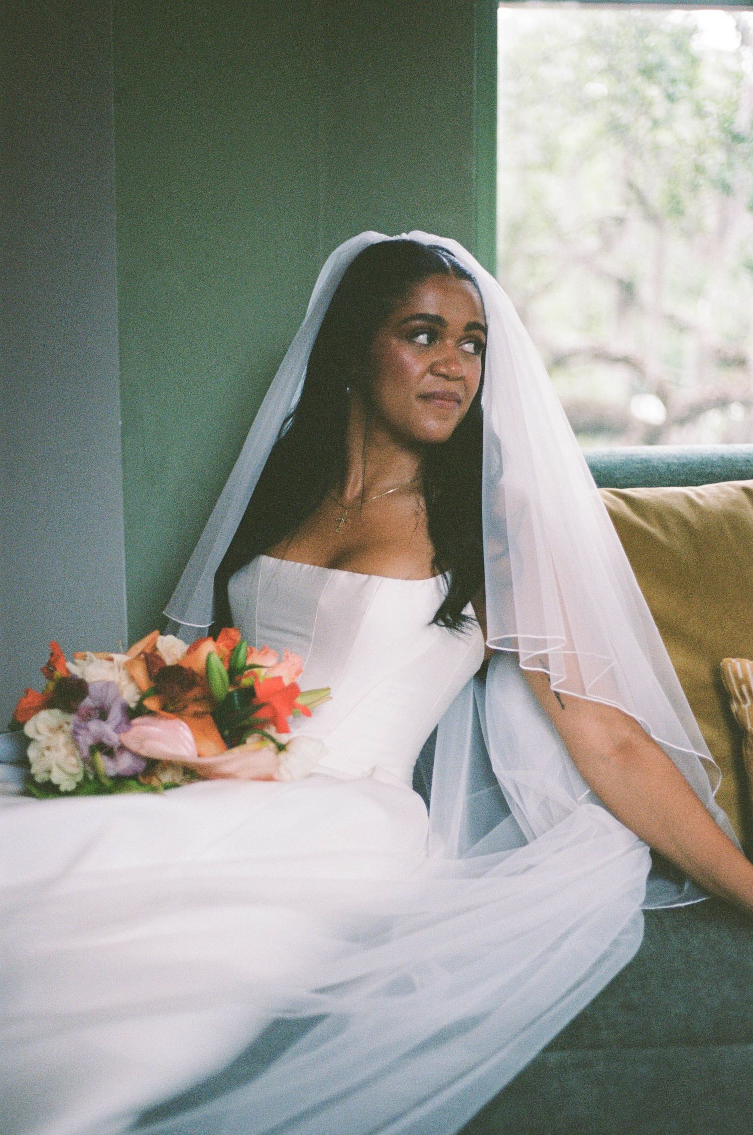 A sequence showing a bride in white veil and dress seated on a couch in natural window light.