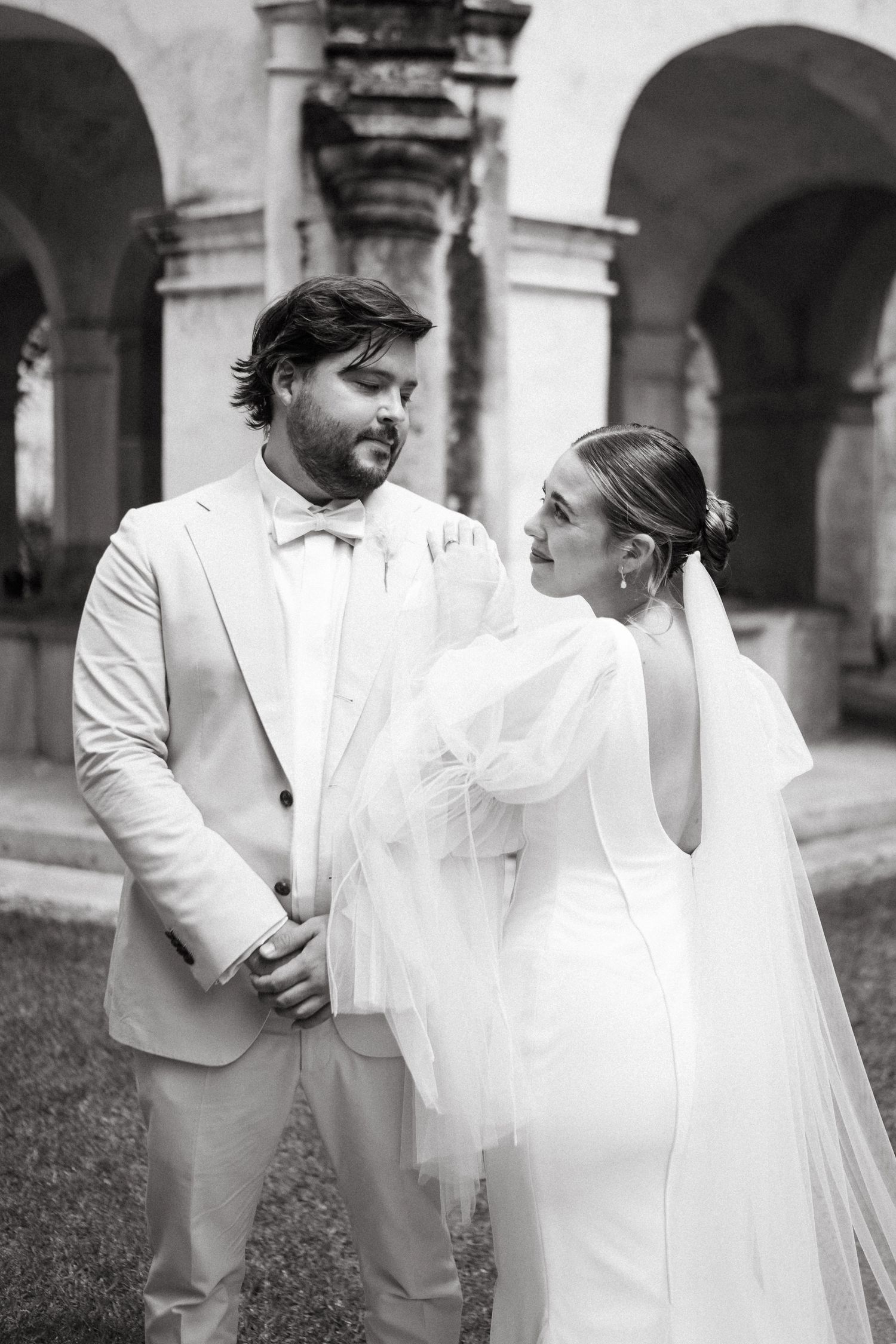 A black and white wedding portrait under classical stone archways.