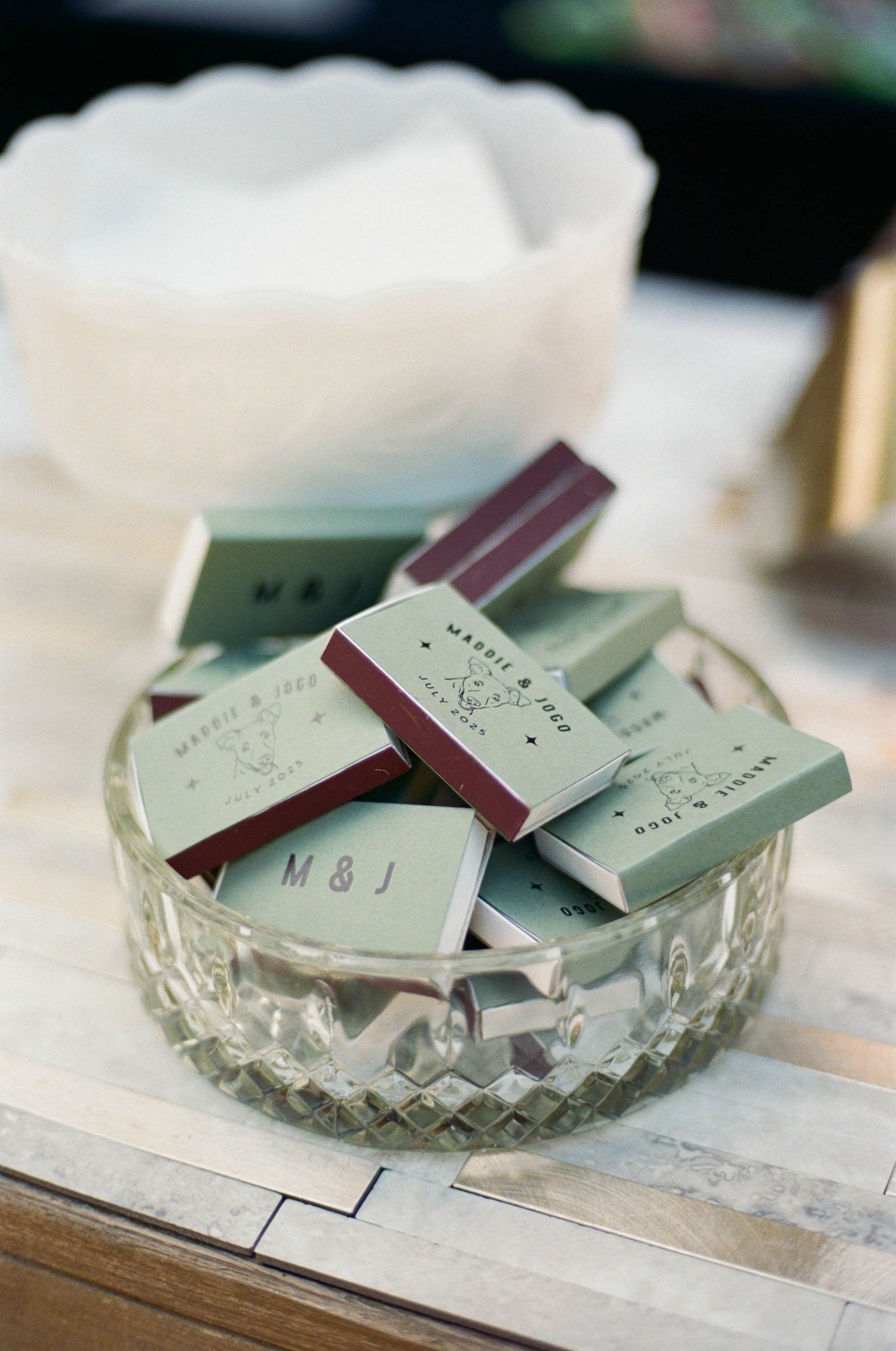 Crystal bowl filled with mint green and burgundy matchbooks with monogram initials.