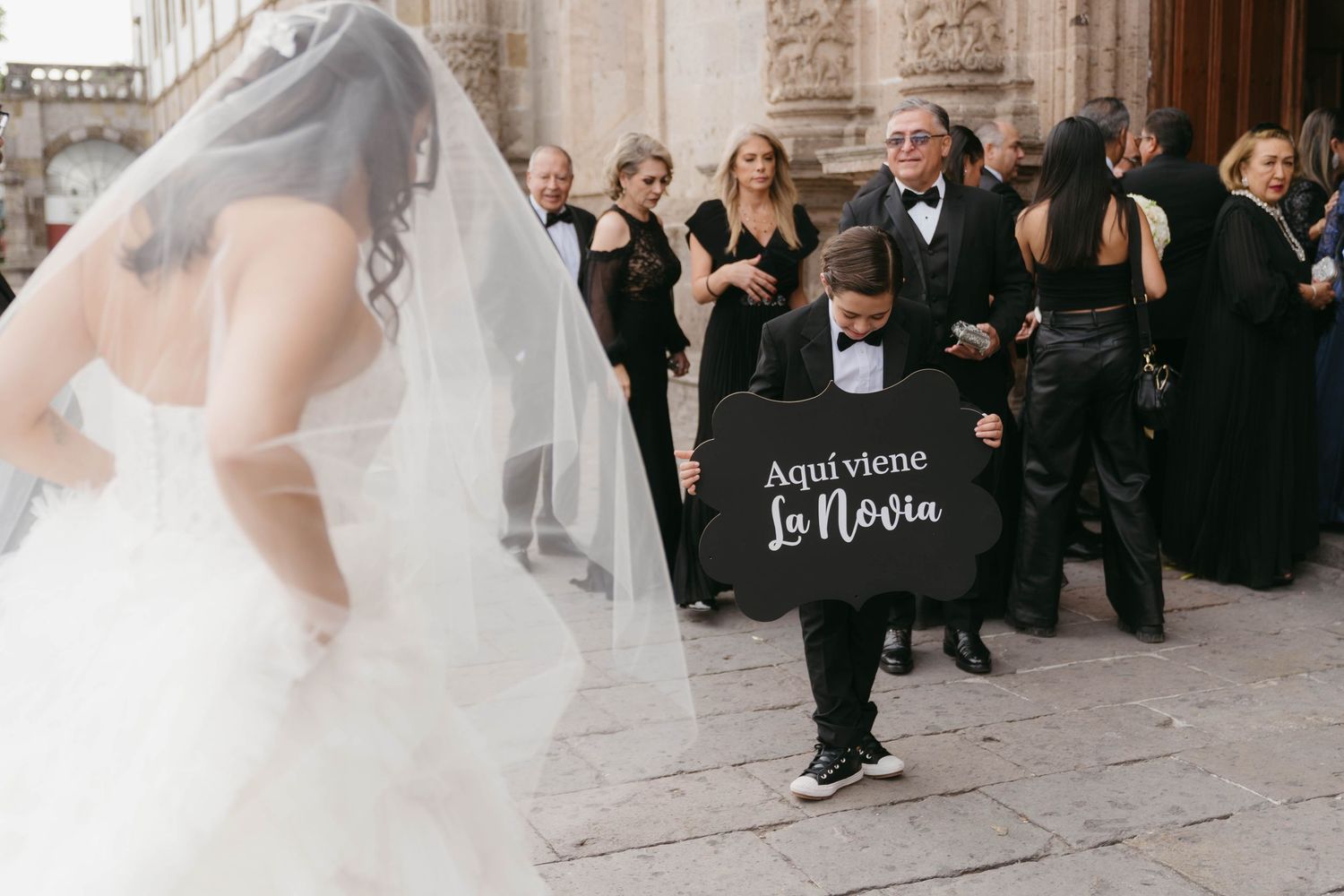 Wedding guests gather outside a historic stone church during a celebration.
