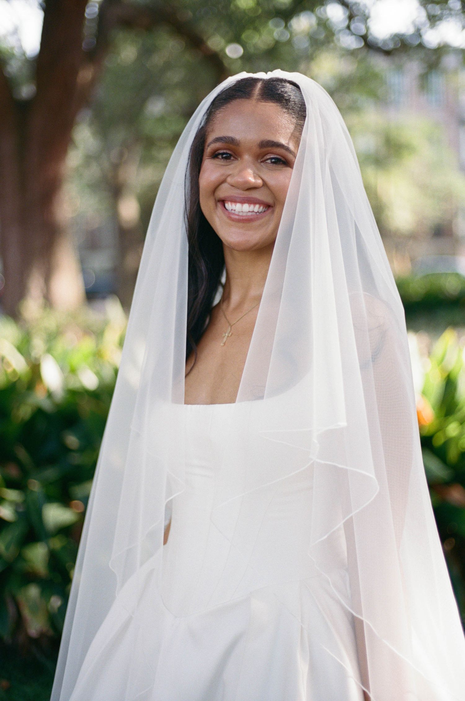 Ethereal bridal portrait showing flowing white veil against garden background.