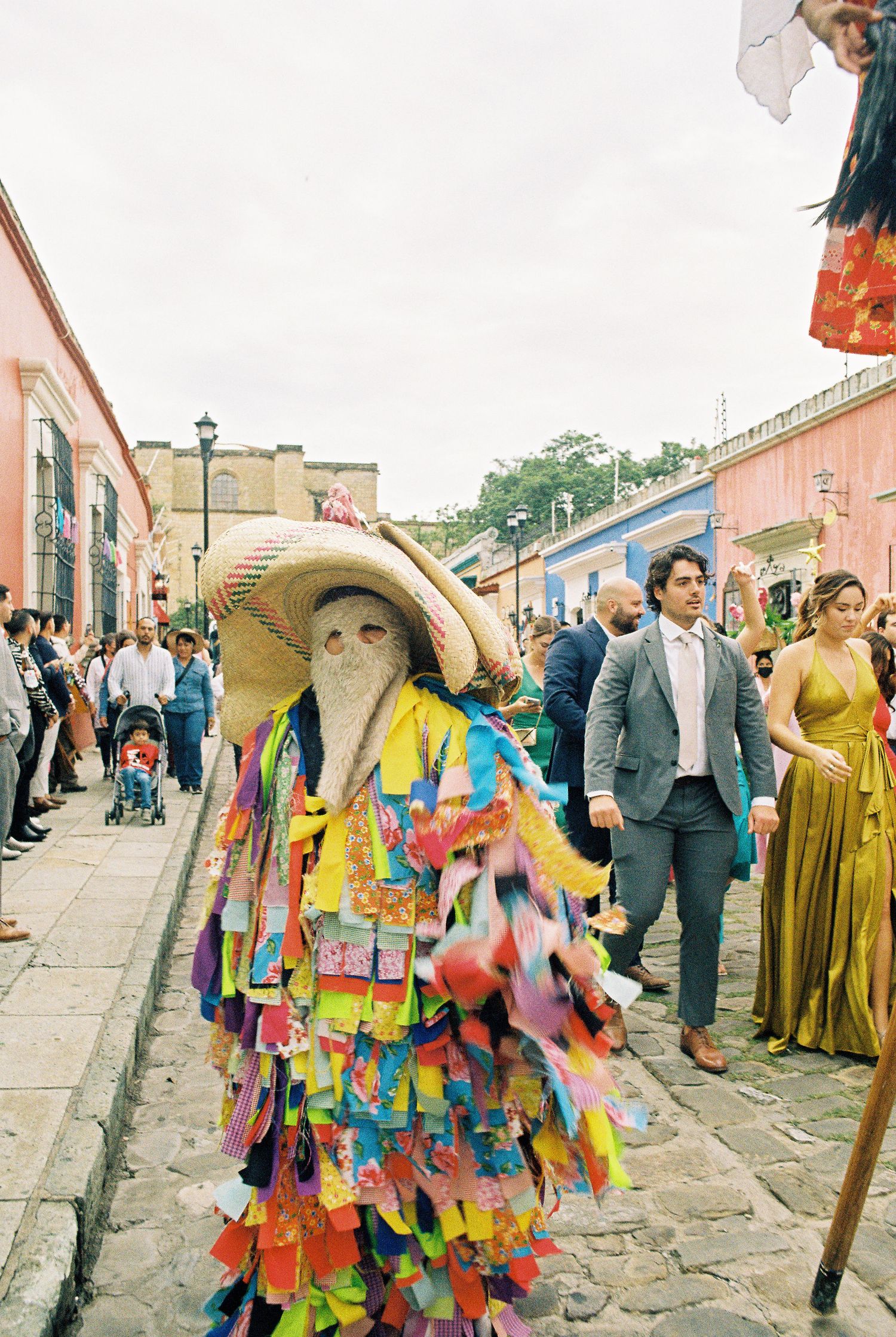 Festive street parade with dancers wearing vibrant multicolored costumes and golden dresses.