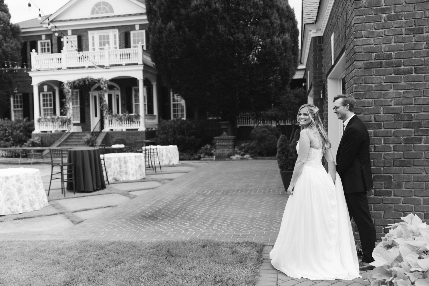 Bride and groom share a romantic black and white moment outside a classic Southern mansion venue.