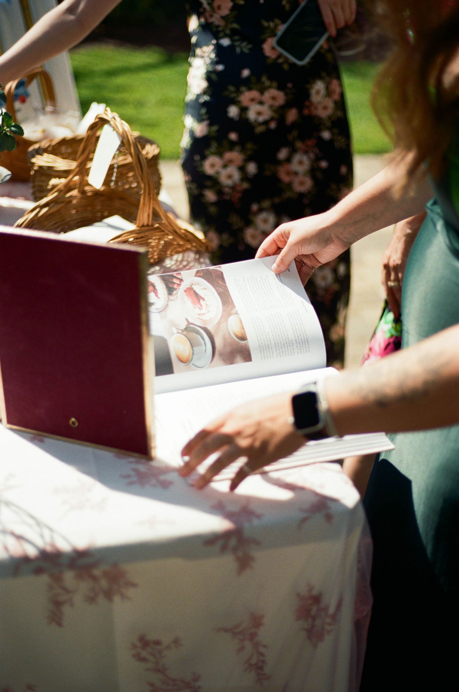 Guests signing a guestbook at an outdoor event with floral decorations.