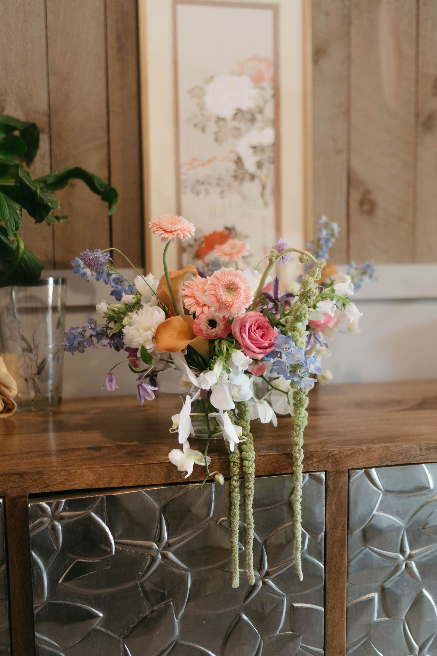 Delicate floral arrangements with pink and purple blooms displayed on wooden table.