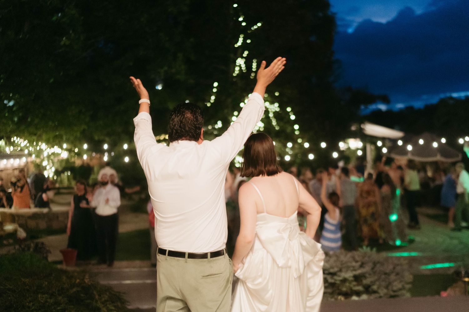 Evening wedding reception under string lights with mountains visible in background.