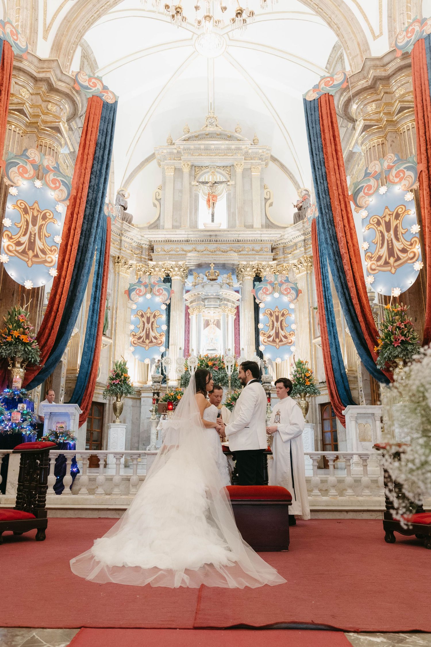Grand church interior with baroque architecture, crystal chandeliers, and red carpet for wedding ceremony.