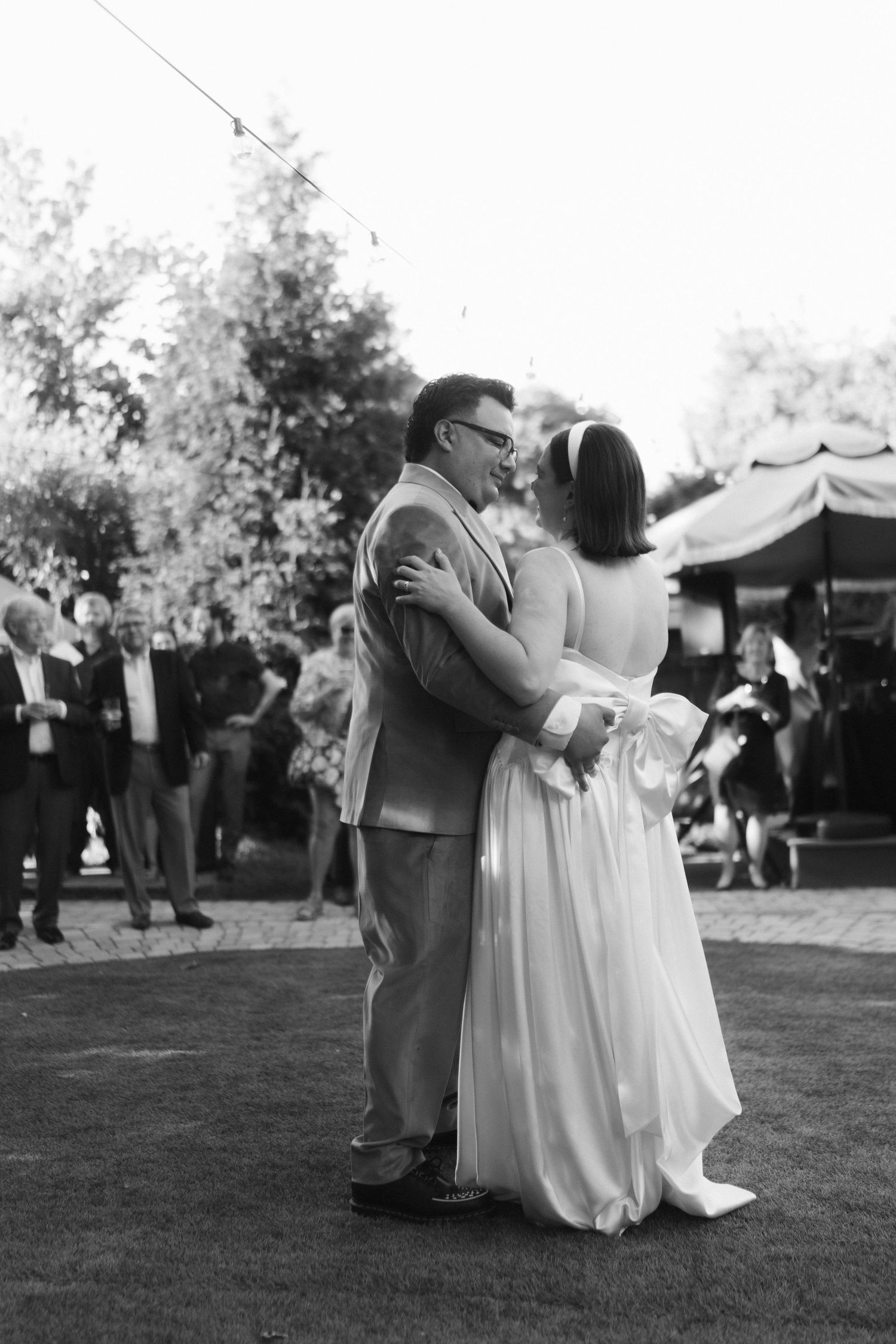 Black and white photo of newlyweds dancing together at an outdoor reception.
