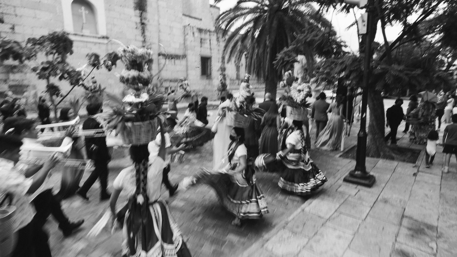 Black and white panoramic sequence showing a lively outdoor wedding reception celebration.