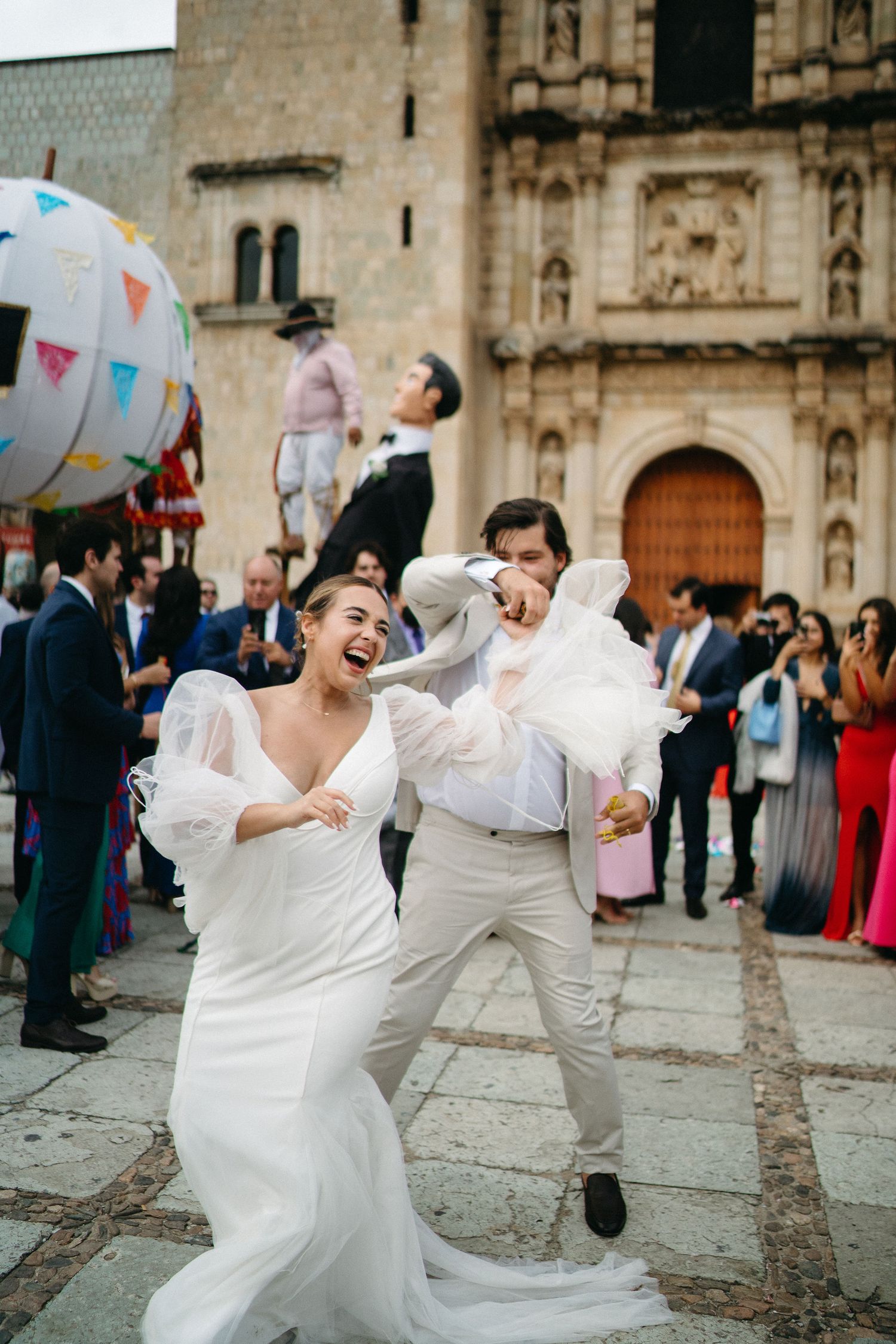 Energetic wedding celebration with dancing and laughter outside a historic church entrance.