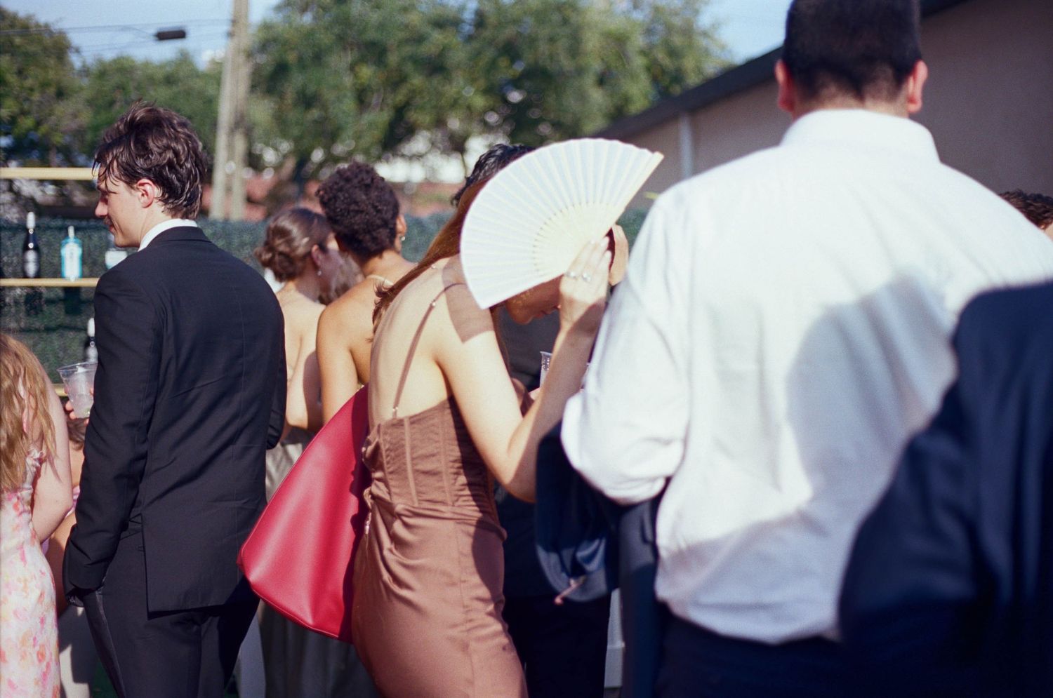 Wedding guests gather outdoors during a daytime celebration.