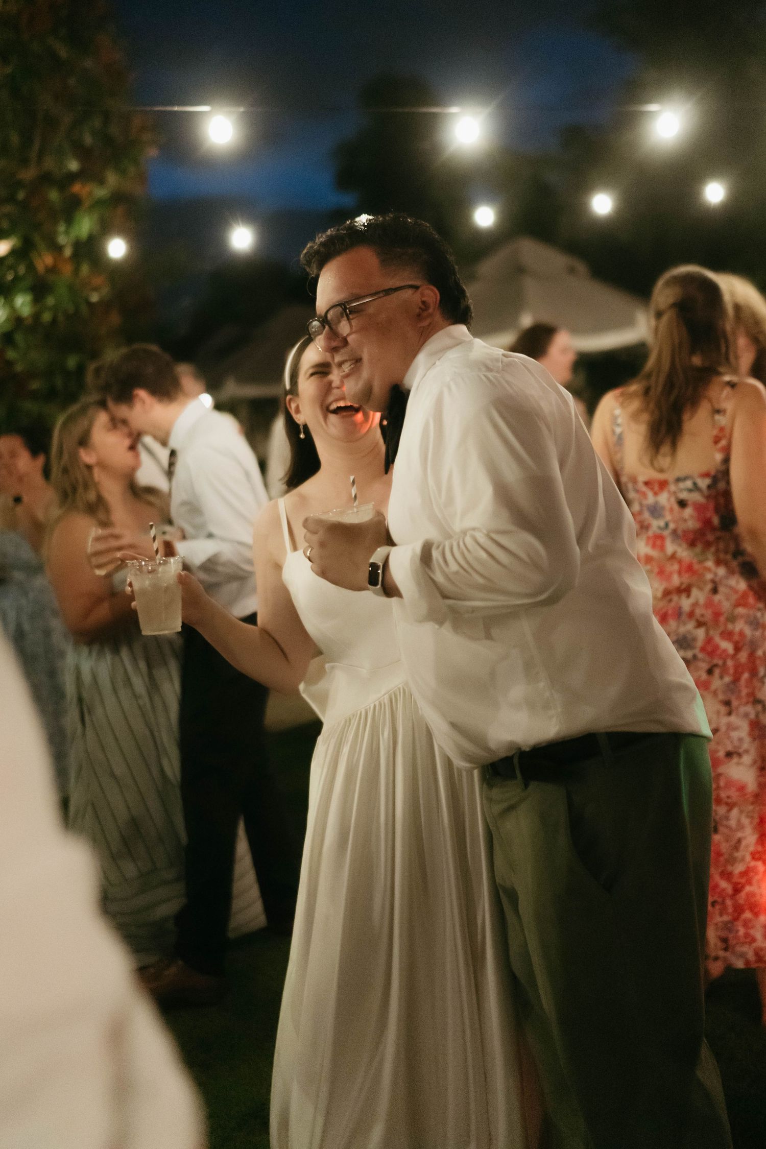 Wedding celebration on an outdoor dance floor with string lights overhead.