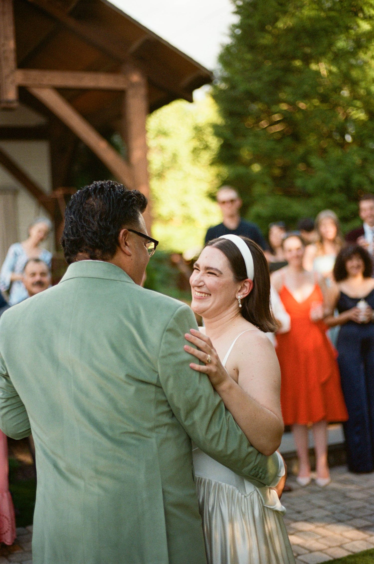Couple sharing first dance on brick patio during garden wedding reception.