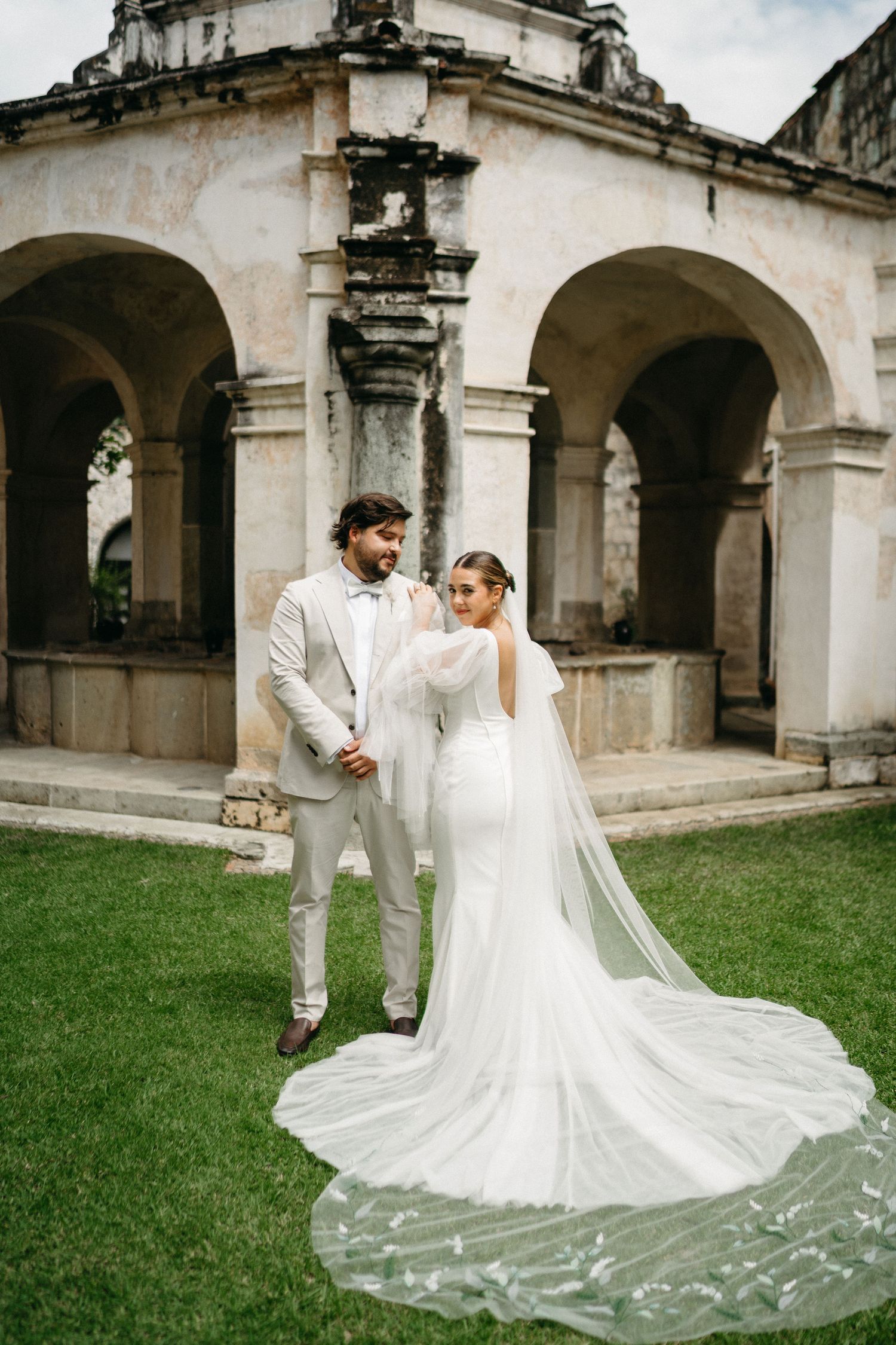 Elegant wedding dress with long train photographed against historic stone colonnade.