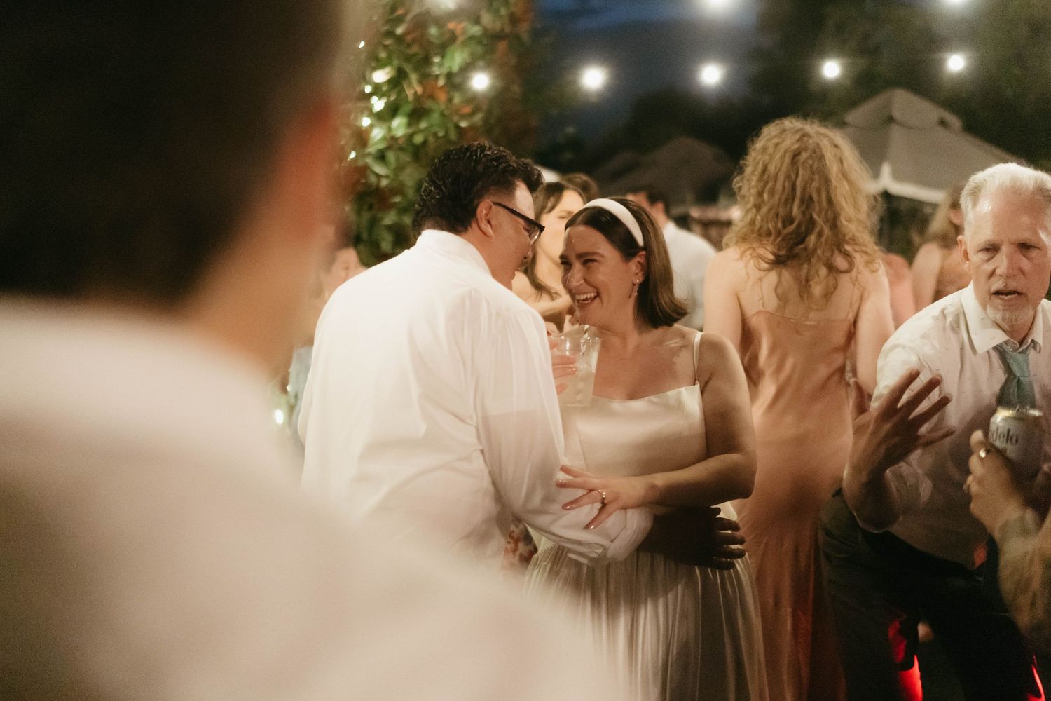 Guests dancing and celebrating at a dimly lit outdoor wedding reception.