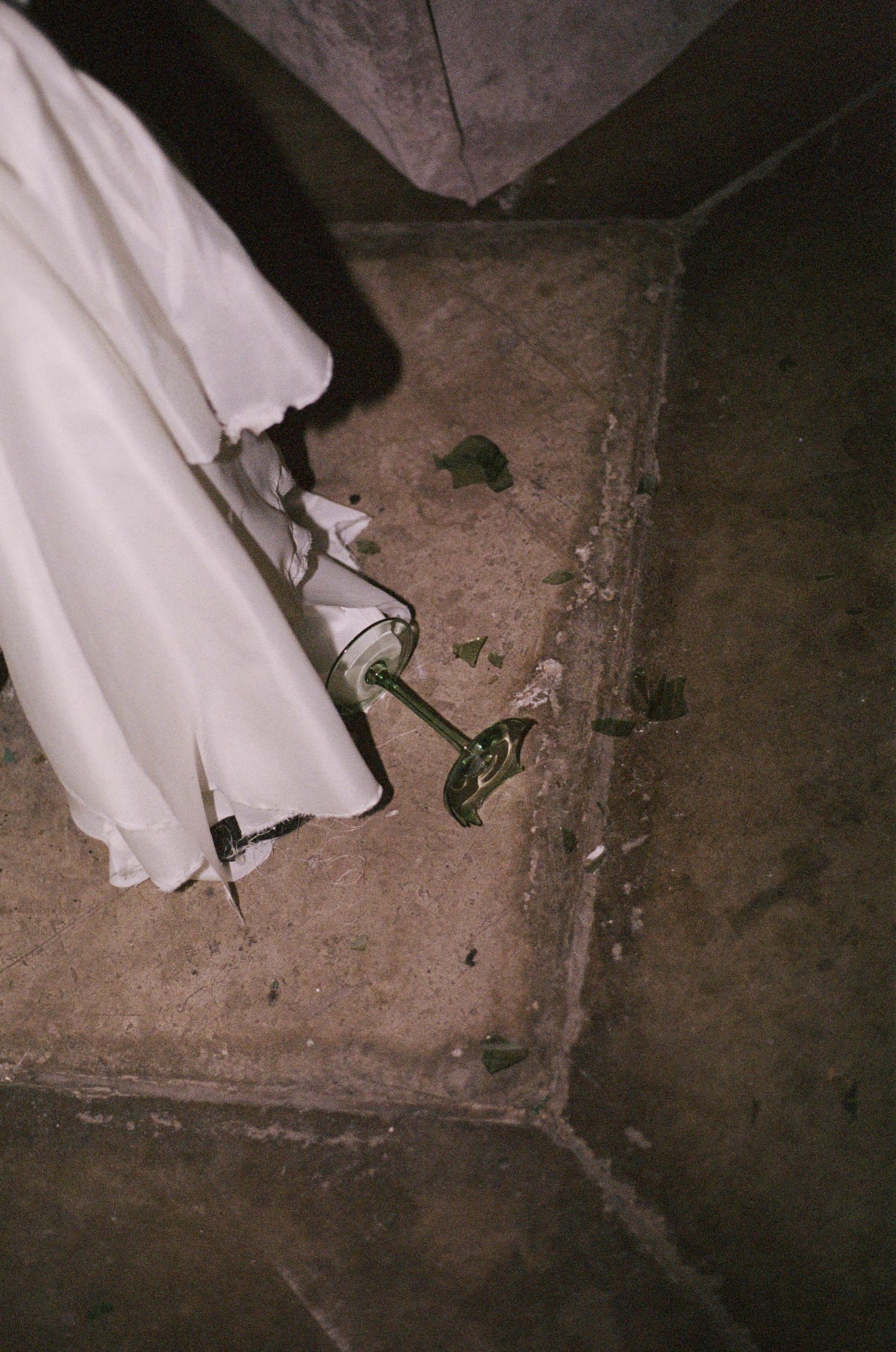 White formal attire and champagne glass visible against concrete floor at event venue.
