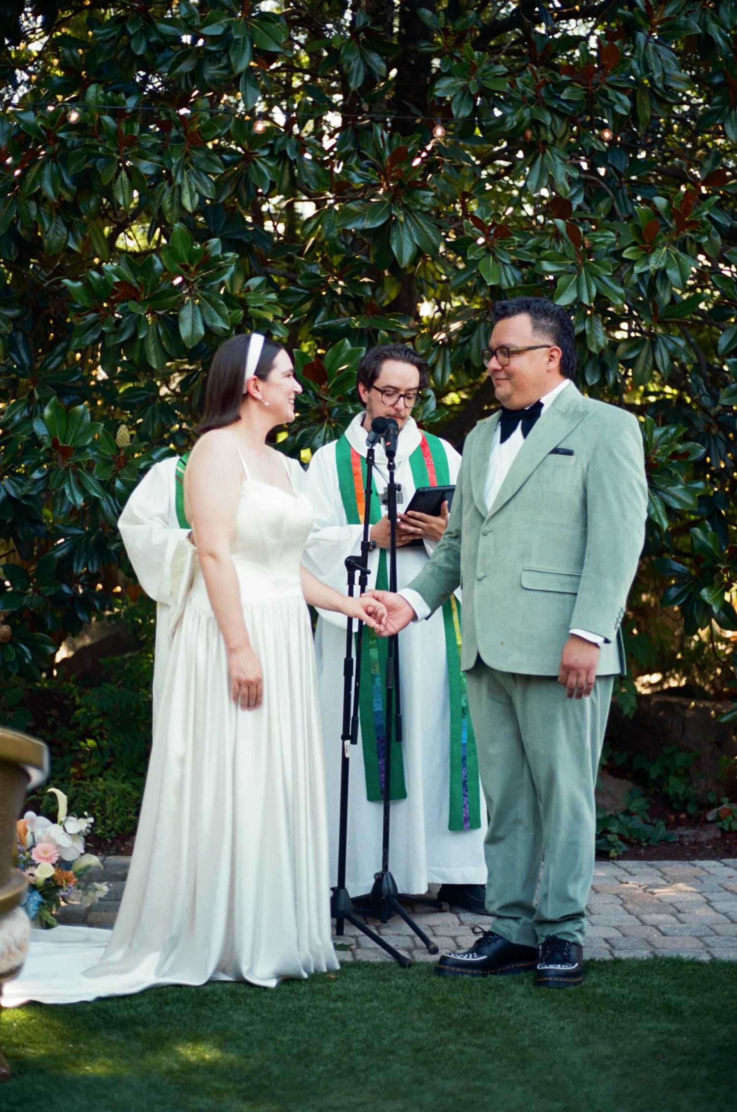 An outdoor wedding ceremony takes place against a backdrop of lush magnolia trees.
