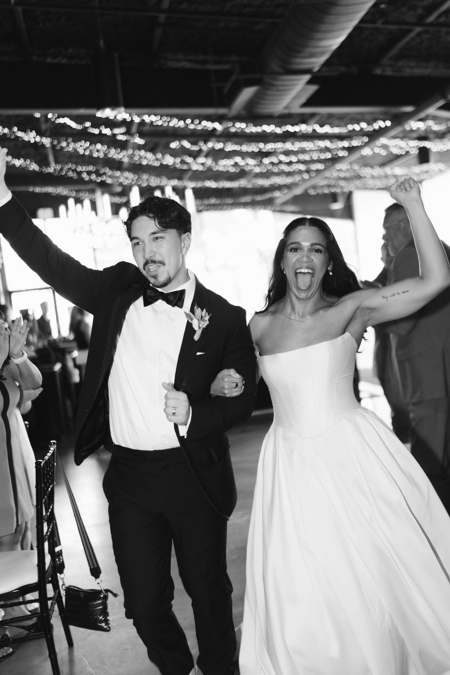 Wedding celebration with people dancing under decorative ceiling lights.