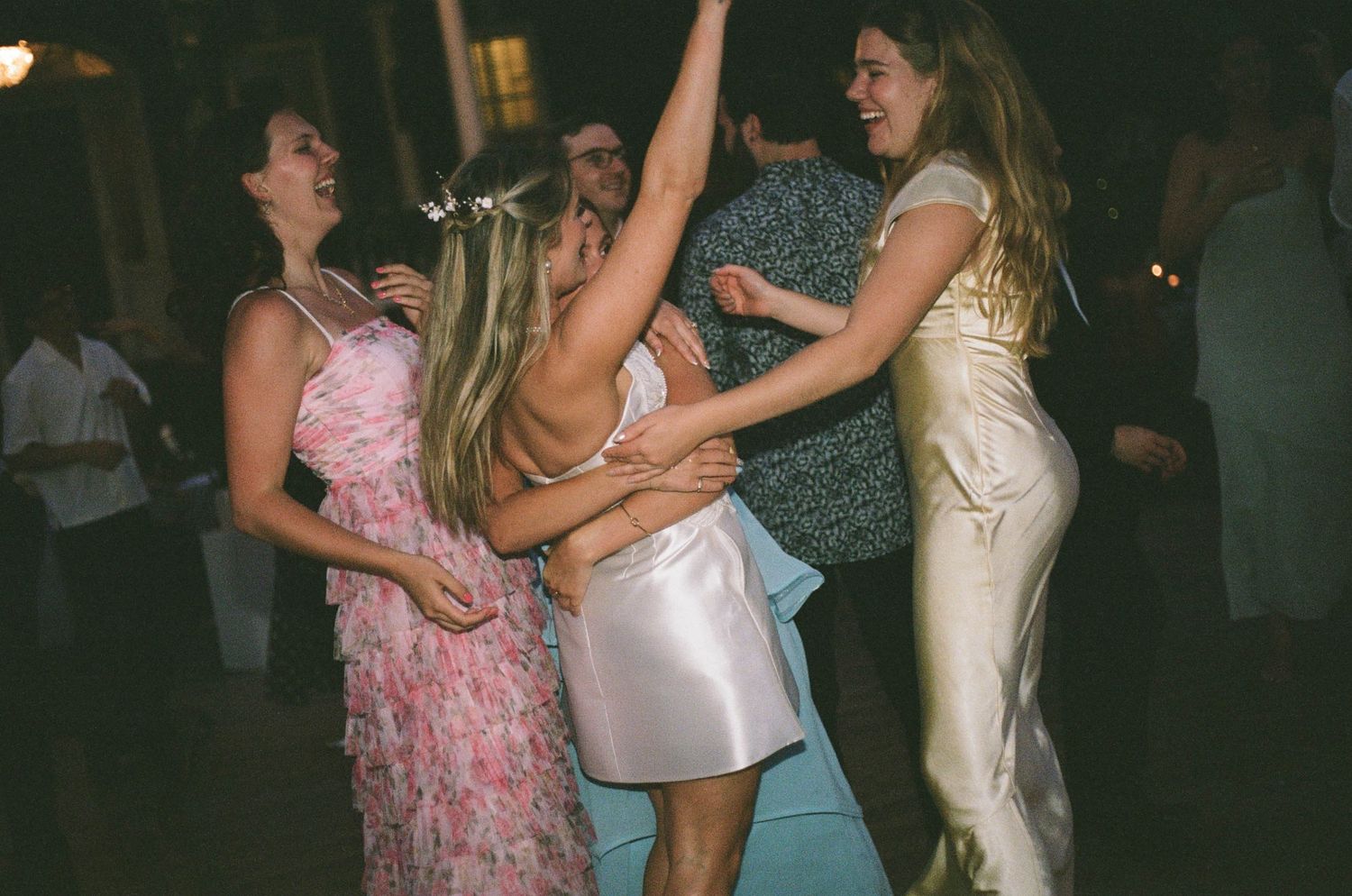 Bridesmaids dancing joyfully at a wedding reception in elegant dresses.