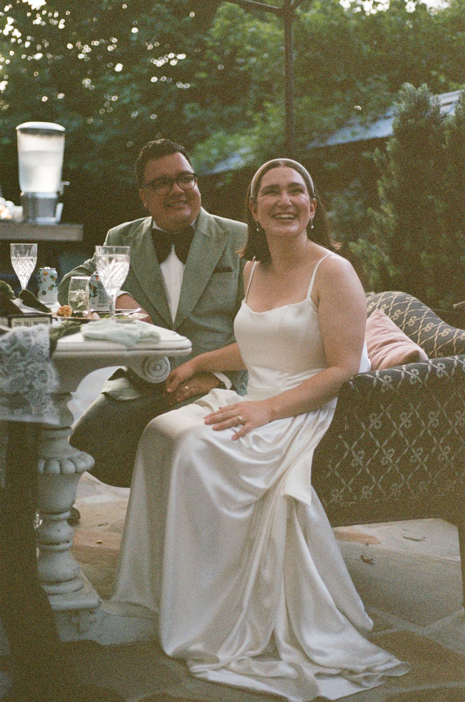 Wedding couple sharing a joyful moment on outdoor patio furniture.