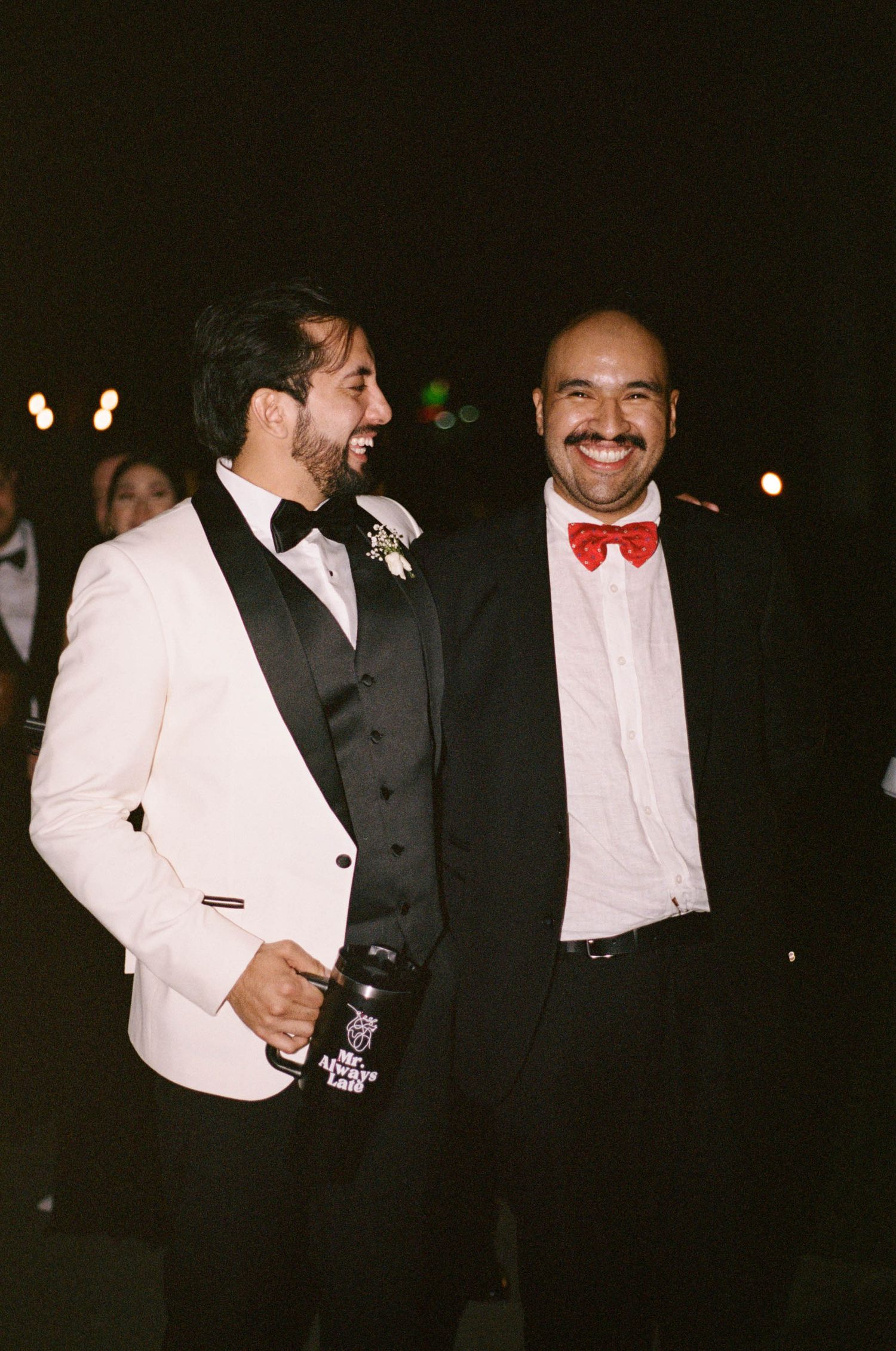 Two gentlemen in formal attire share a moment at an evening celebration.