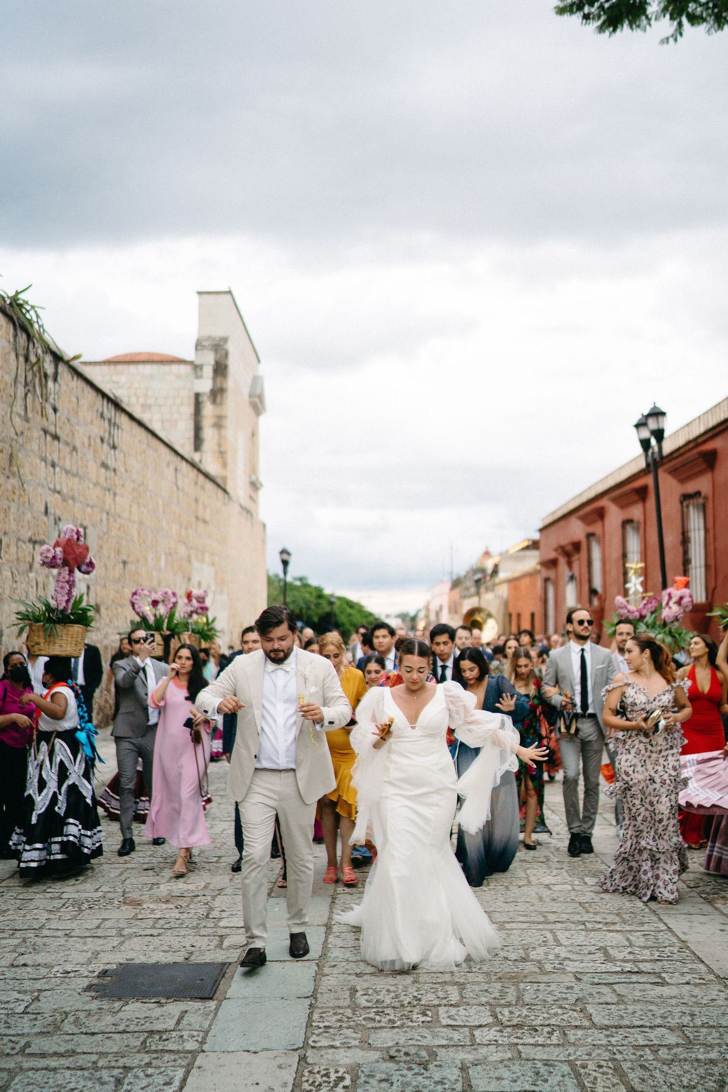 Wedding celebration on historic cobblestone street with guests and stone architecture.