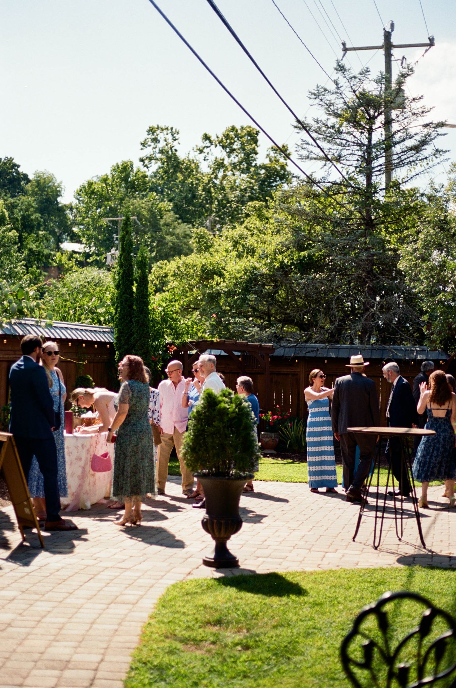 Outdoor reception area with stone patio and decorative cypress trees in garden setting.