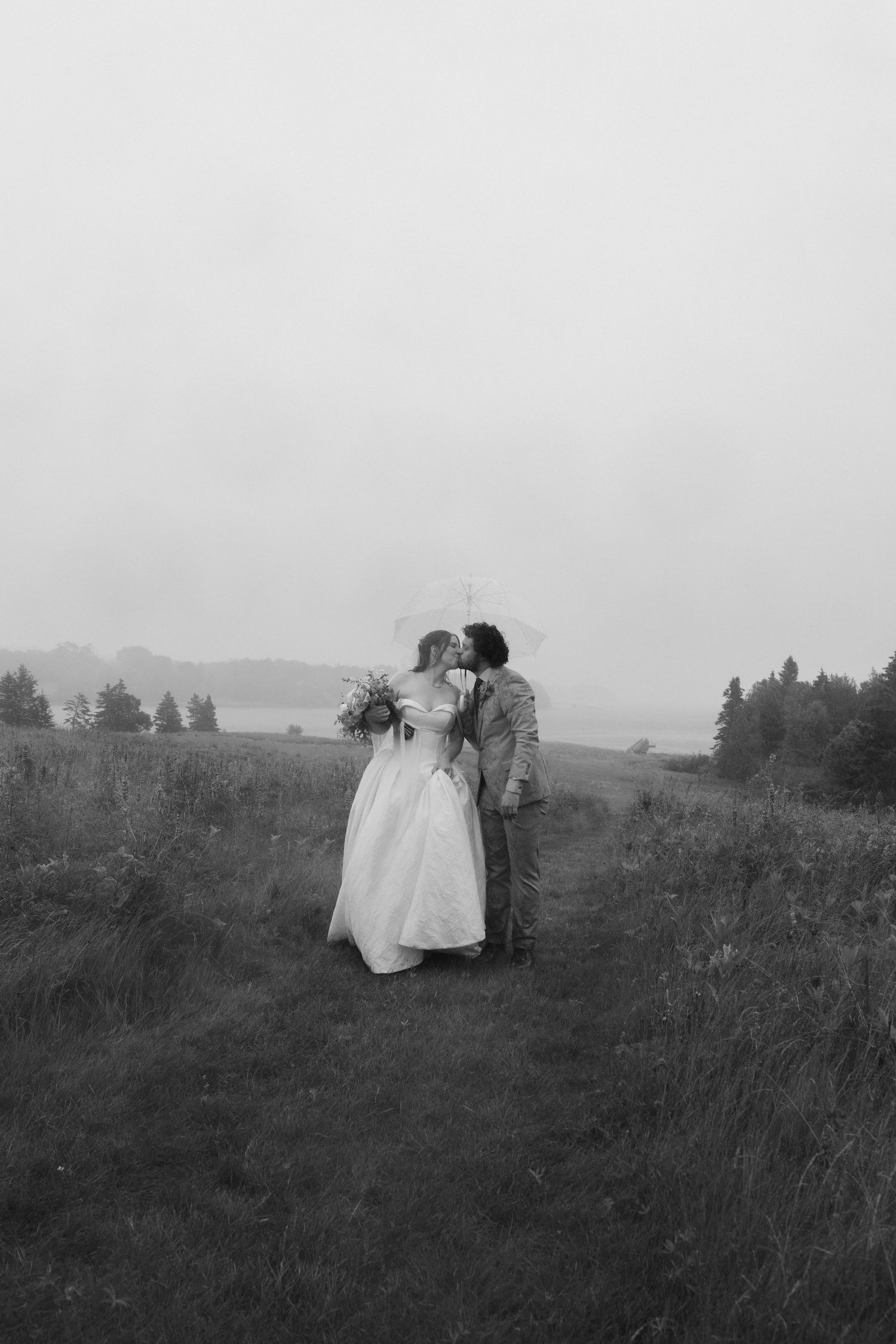 A romantic black and white portrait of newlyweds in a misty field.