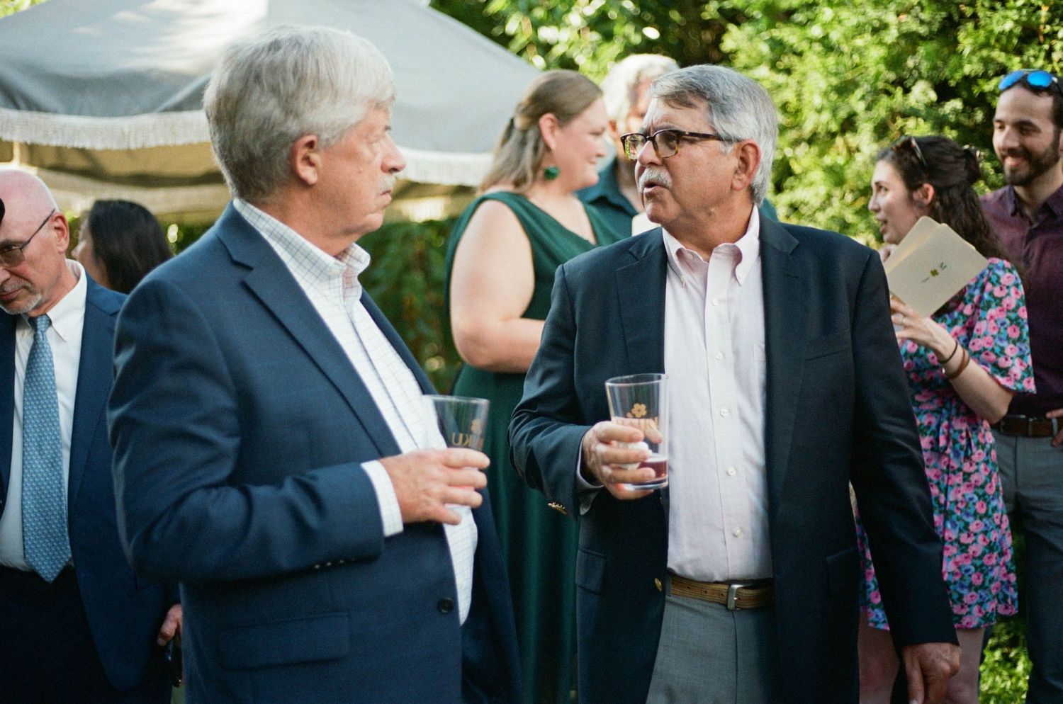 Guests mingling during outdoor cocktail reception in garden setting.