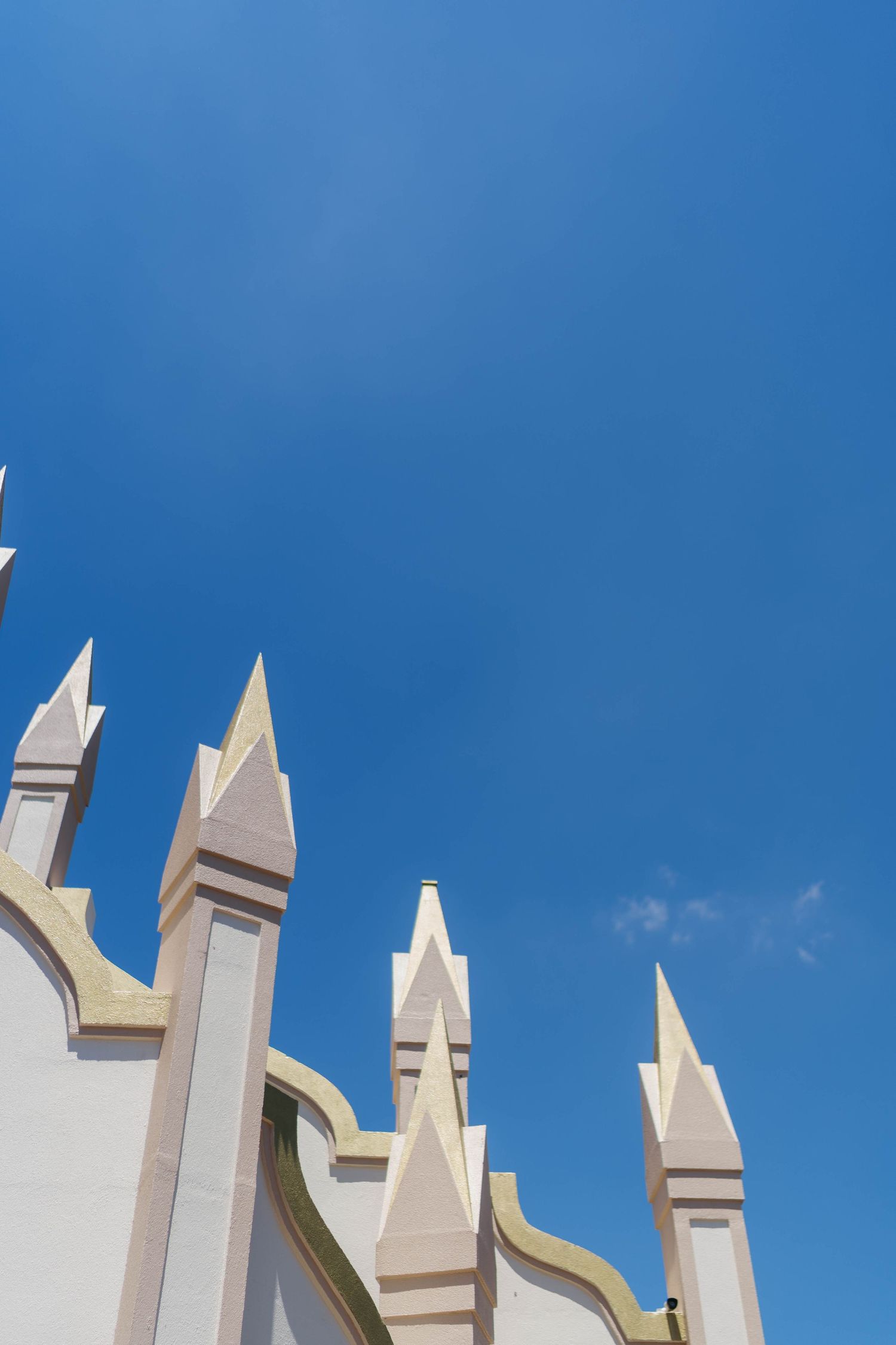 White Gothic architectural spires with gold trim against a clear blue sky.