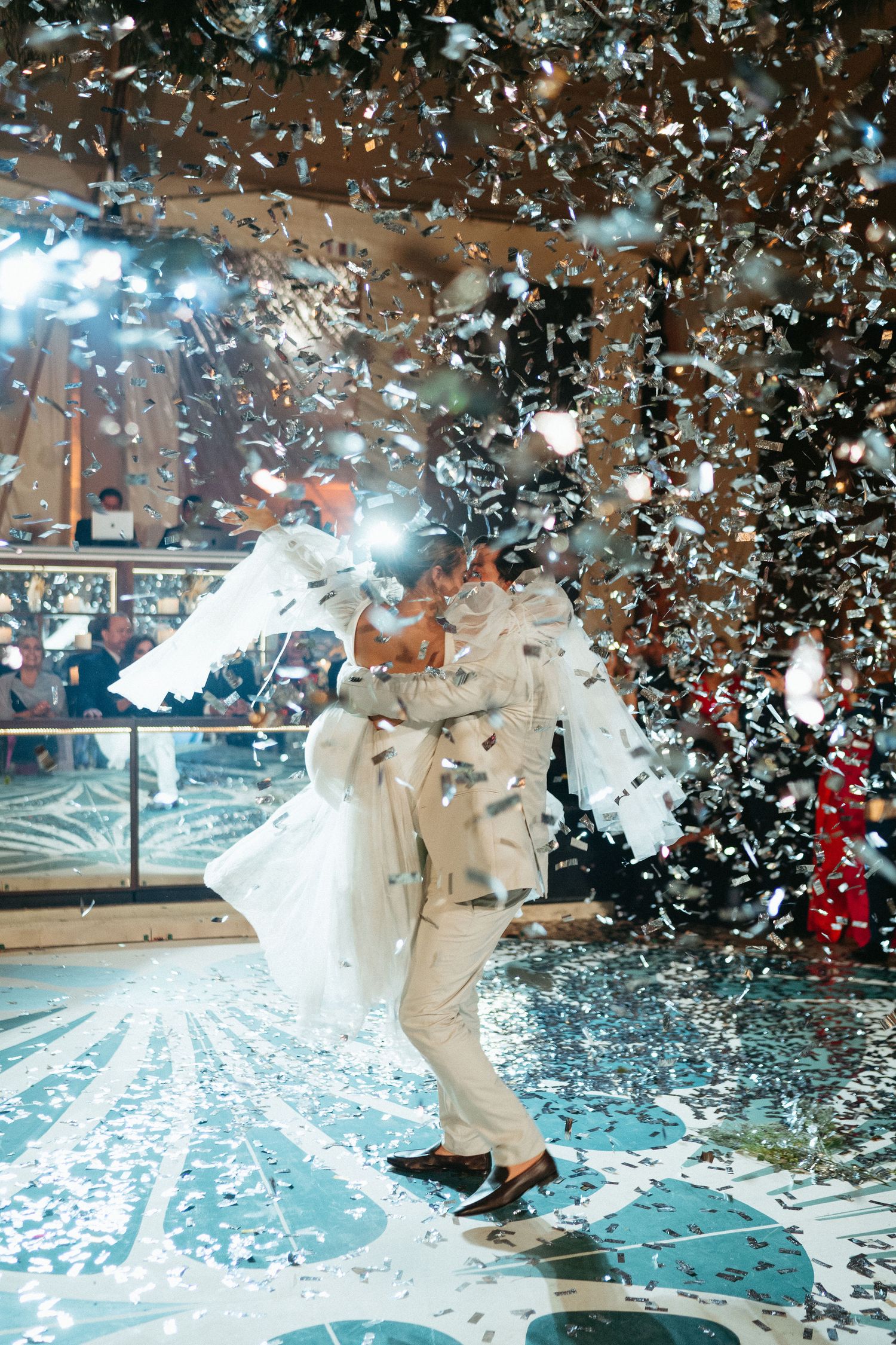 White confetti rains down on dancers during a celebratory wedding moment.
