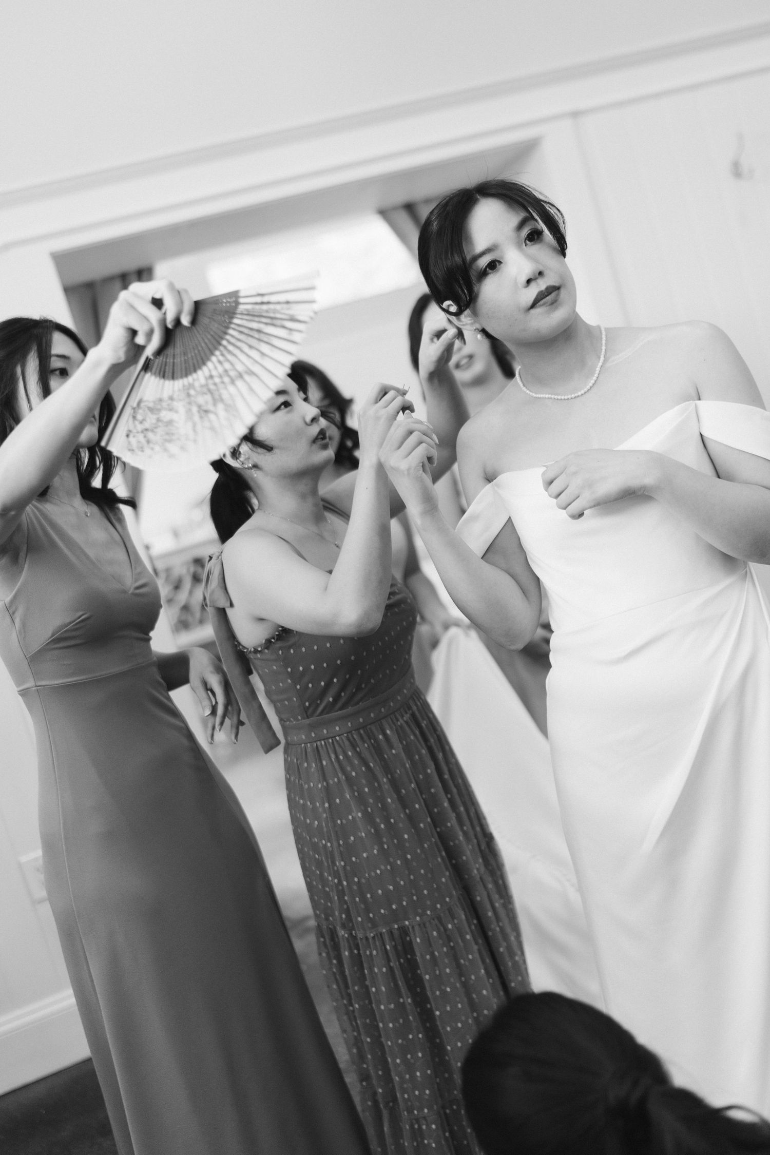 People in casual clothes pose with paper fans while making silly faces indoors.