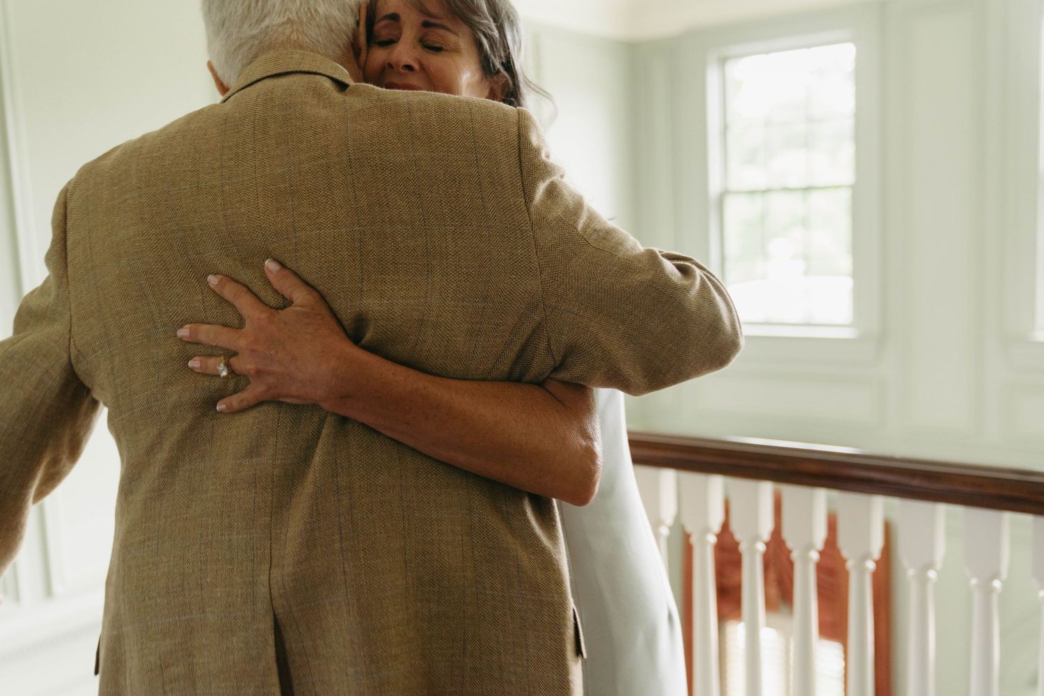 Emotional couple sharing a warm hug near a staircase at a wedding.
