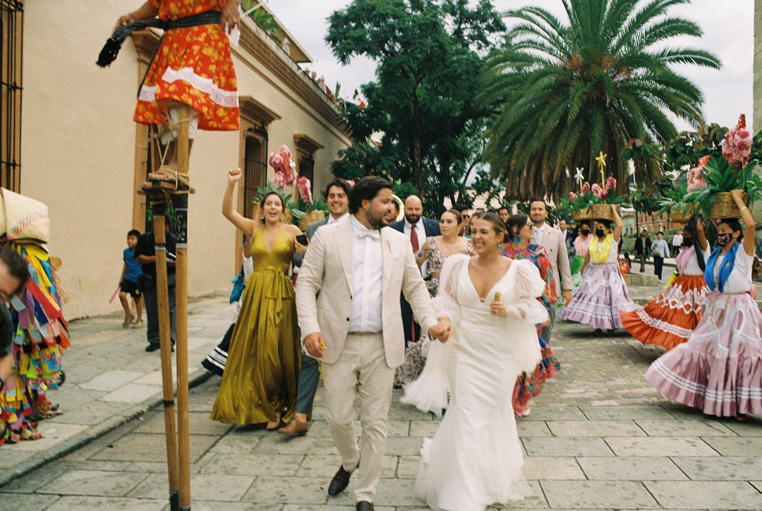 Wedding celebration parade through palm-lined colonial streets with festive decorations.