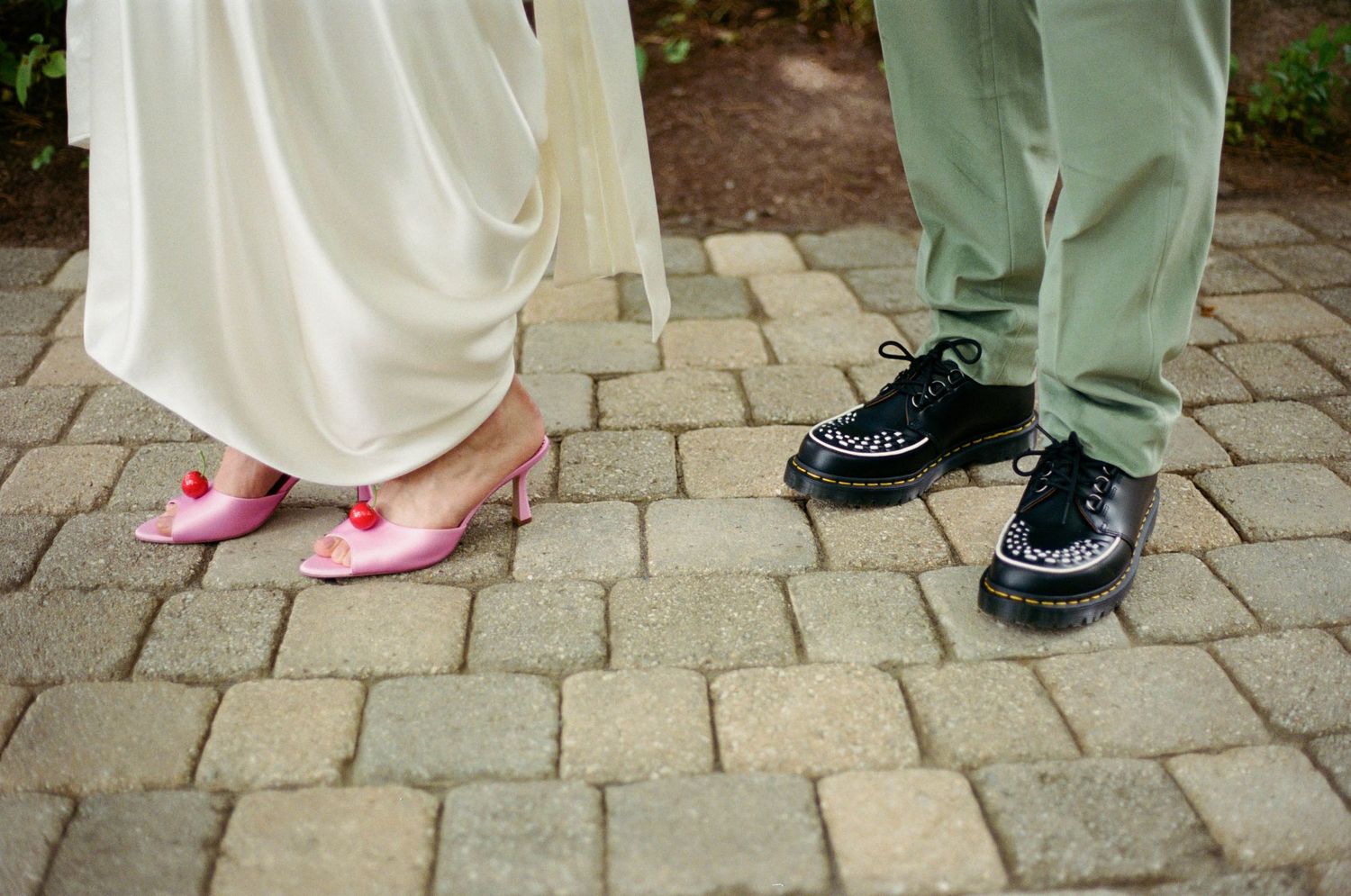 Close-up of contrasting formal shoes on stone paving at outdoor event.
