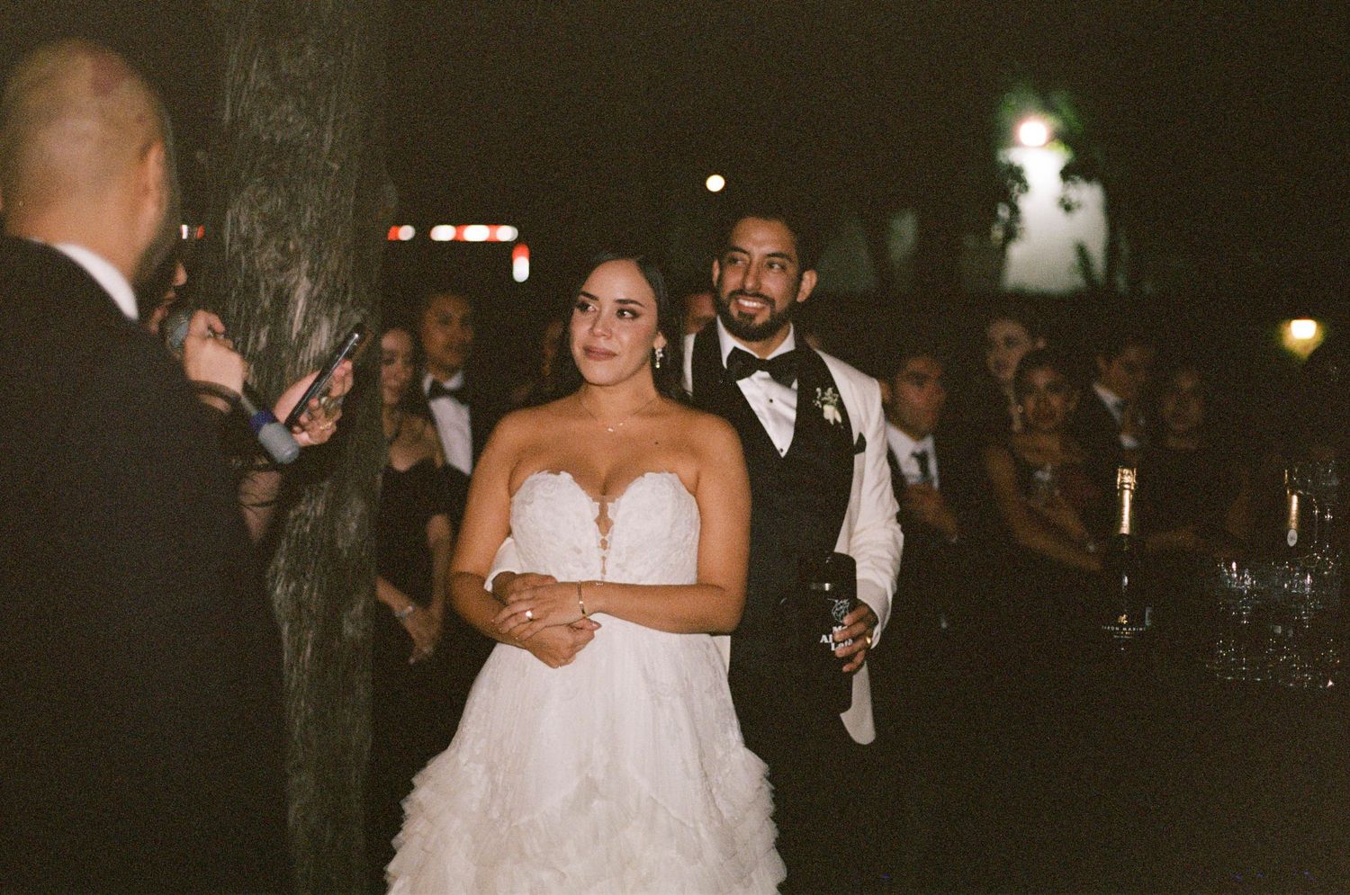 A wedding celebration moment captured outdoors at night with festive lighting.