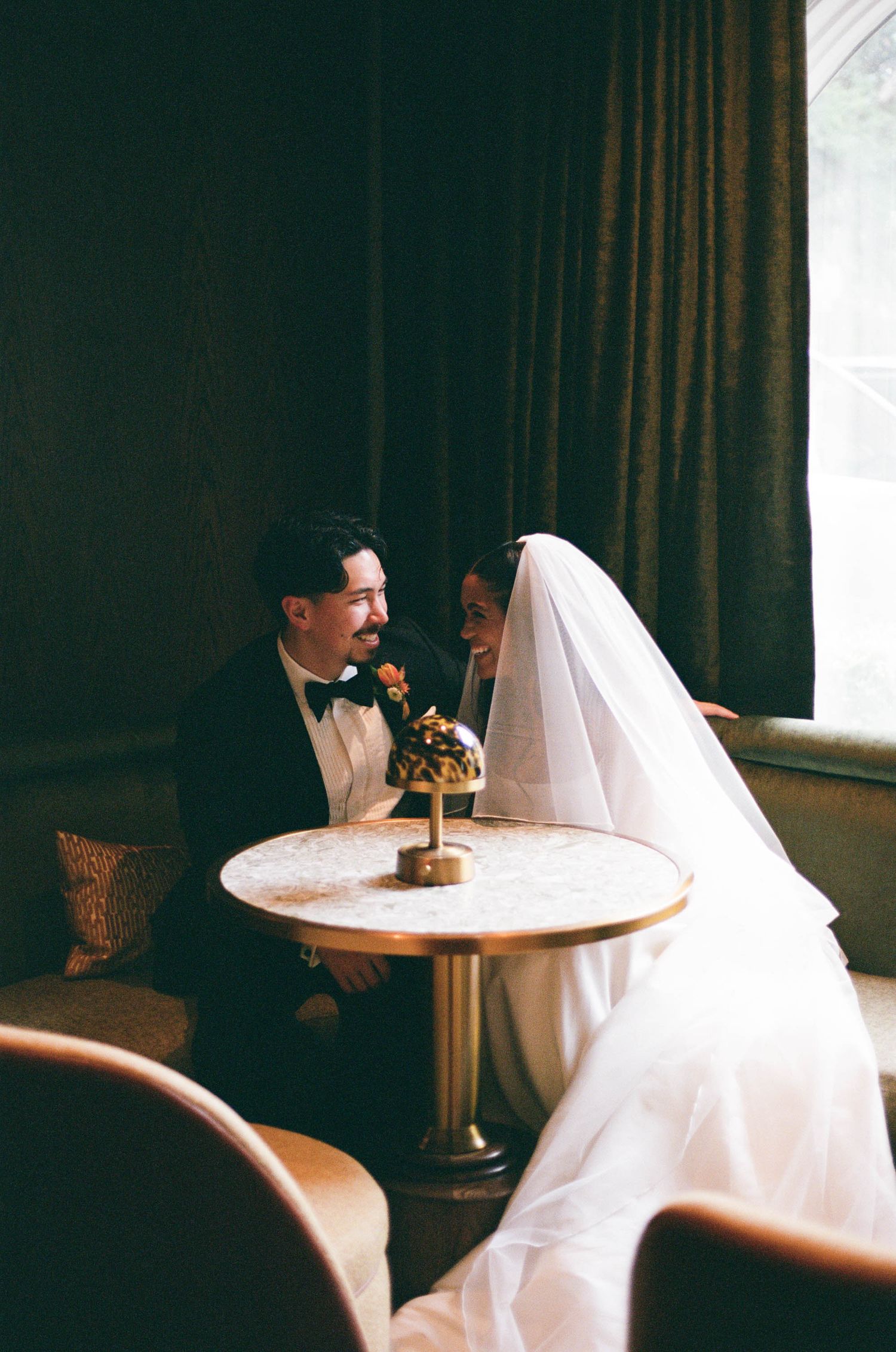 Wedding scene in a dimly lit room with figures seated at a small round table.