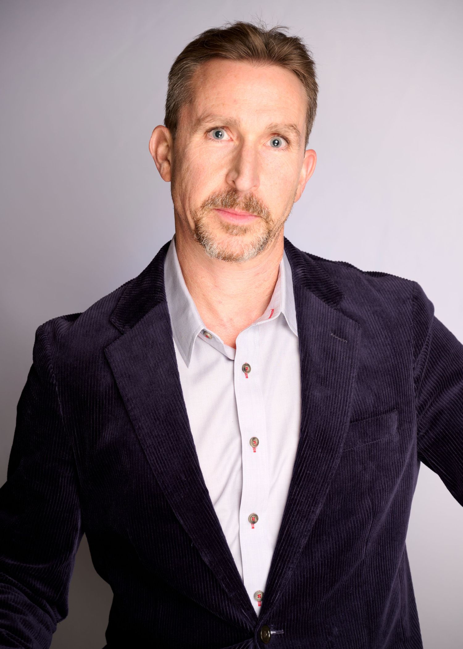 Studio portrait series showing different angles in dark blazer and white shirt.
