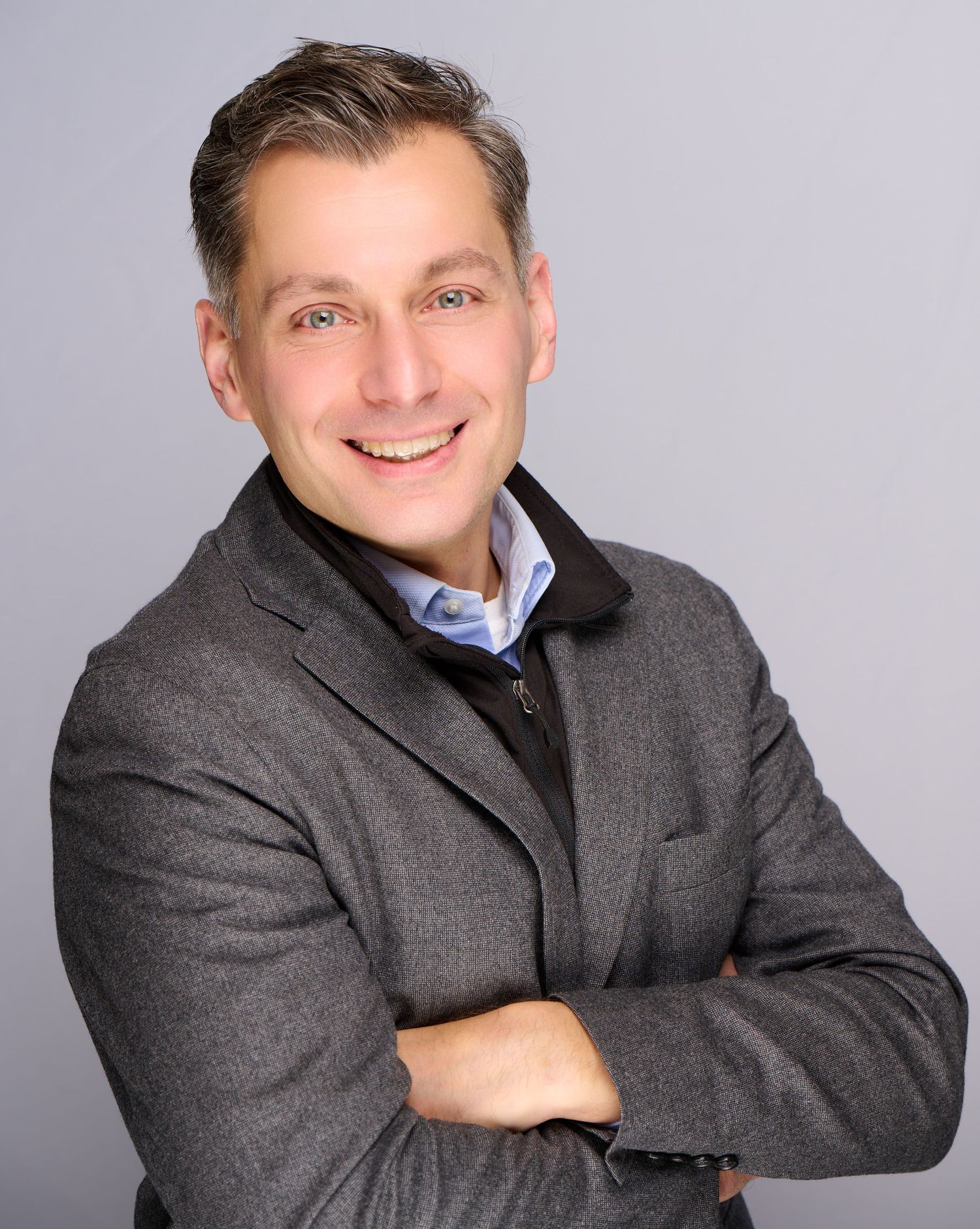 Professional portrait series showing poses in dark suit jacket against gray studio background.