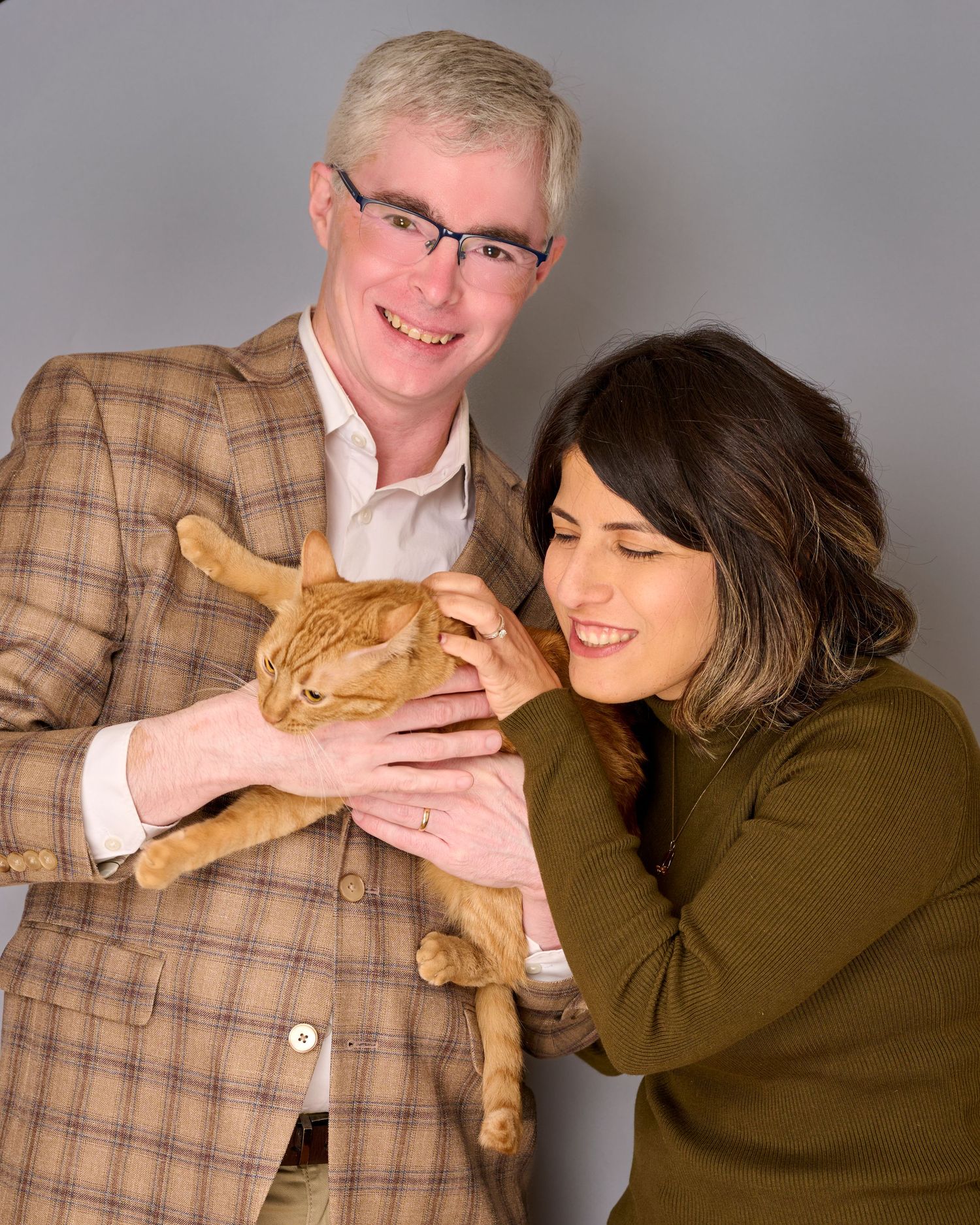 Studio portraits with ginger cat and casual autumn outfits against gray background.