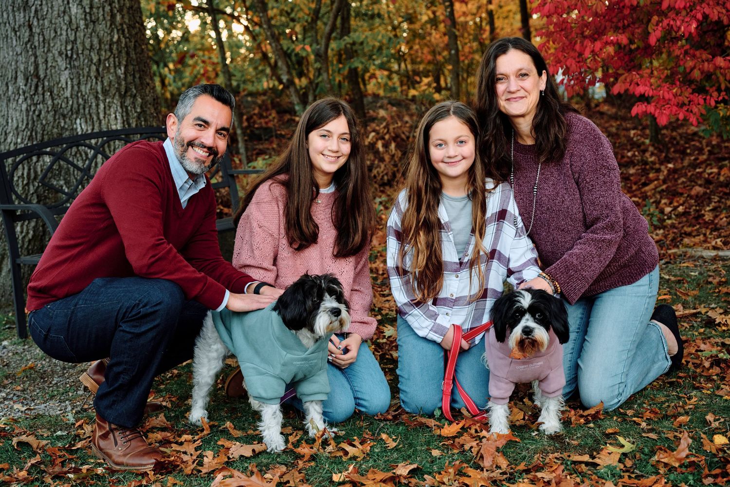Family portrait with pets among vibrant fall foliage and autumn colors.