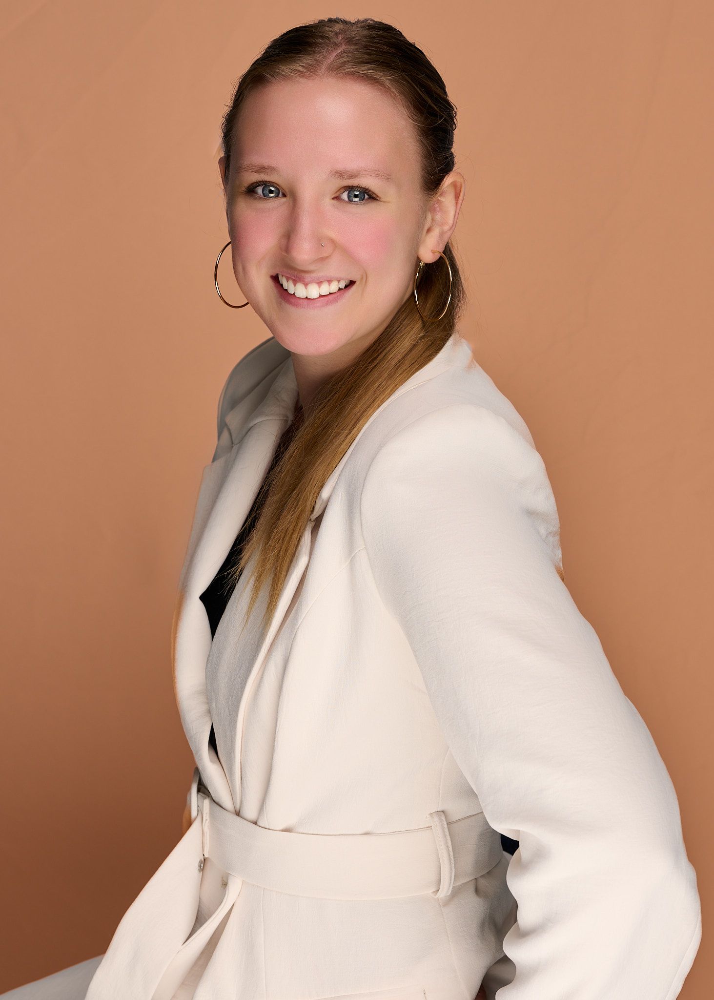 Portrait series in white blazer showing different poses against warm brown background.