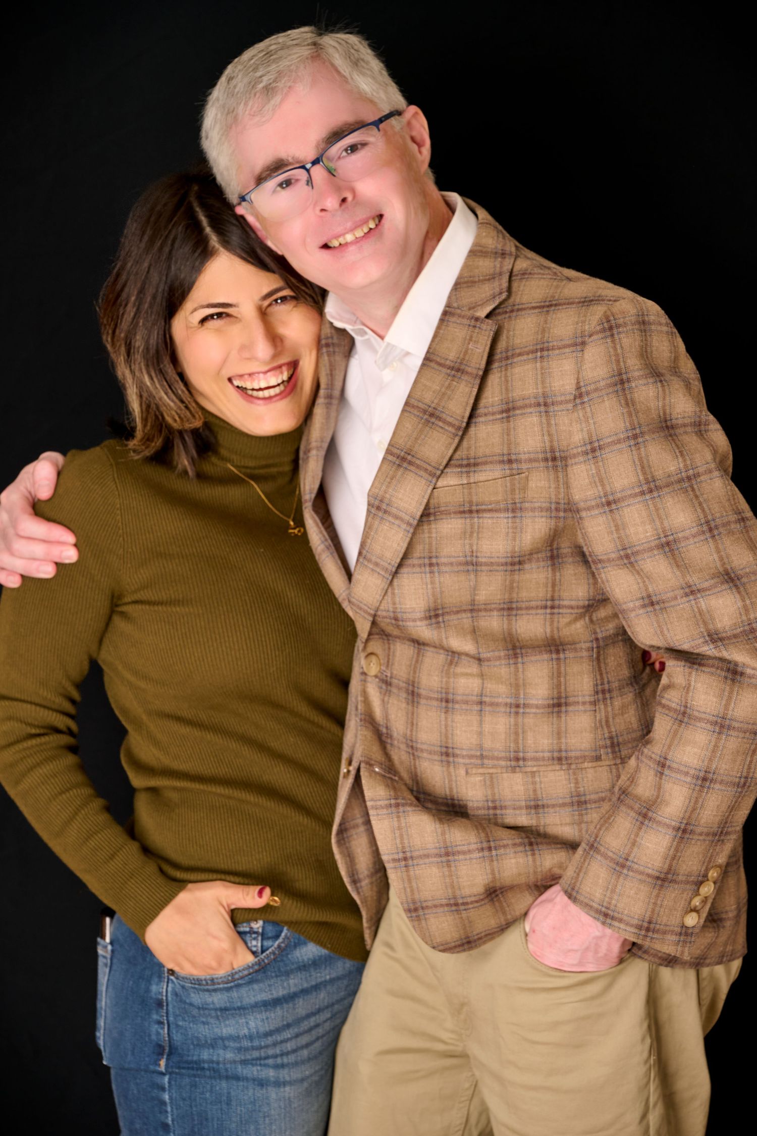 Studio portrait series showing couple in casual wear embracing against dark backdrop.