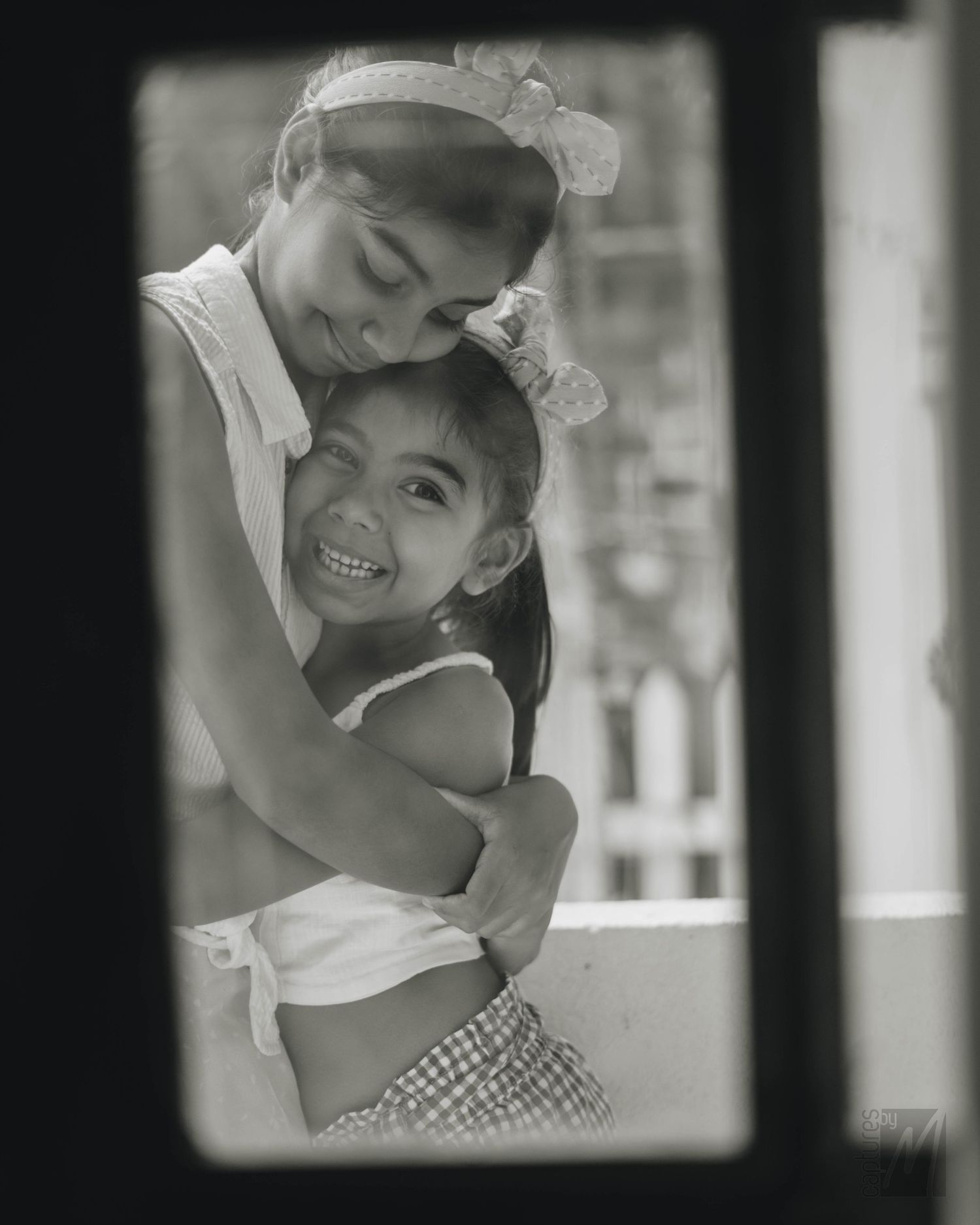 Two little sisters smiling together during a family portrait session