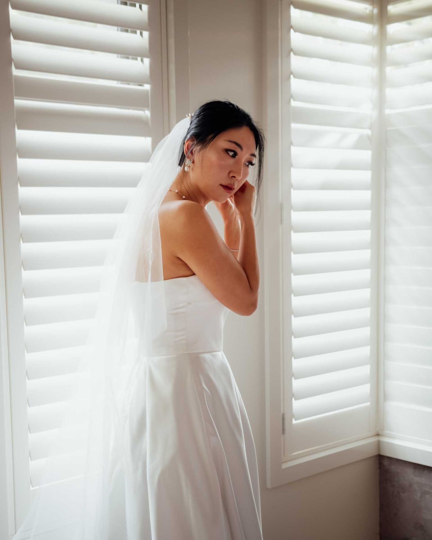 Bride wearing her wedding dress putting her earrings in during a Barossa Valley wedding captured by Matt Webster.
